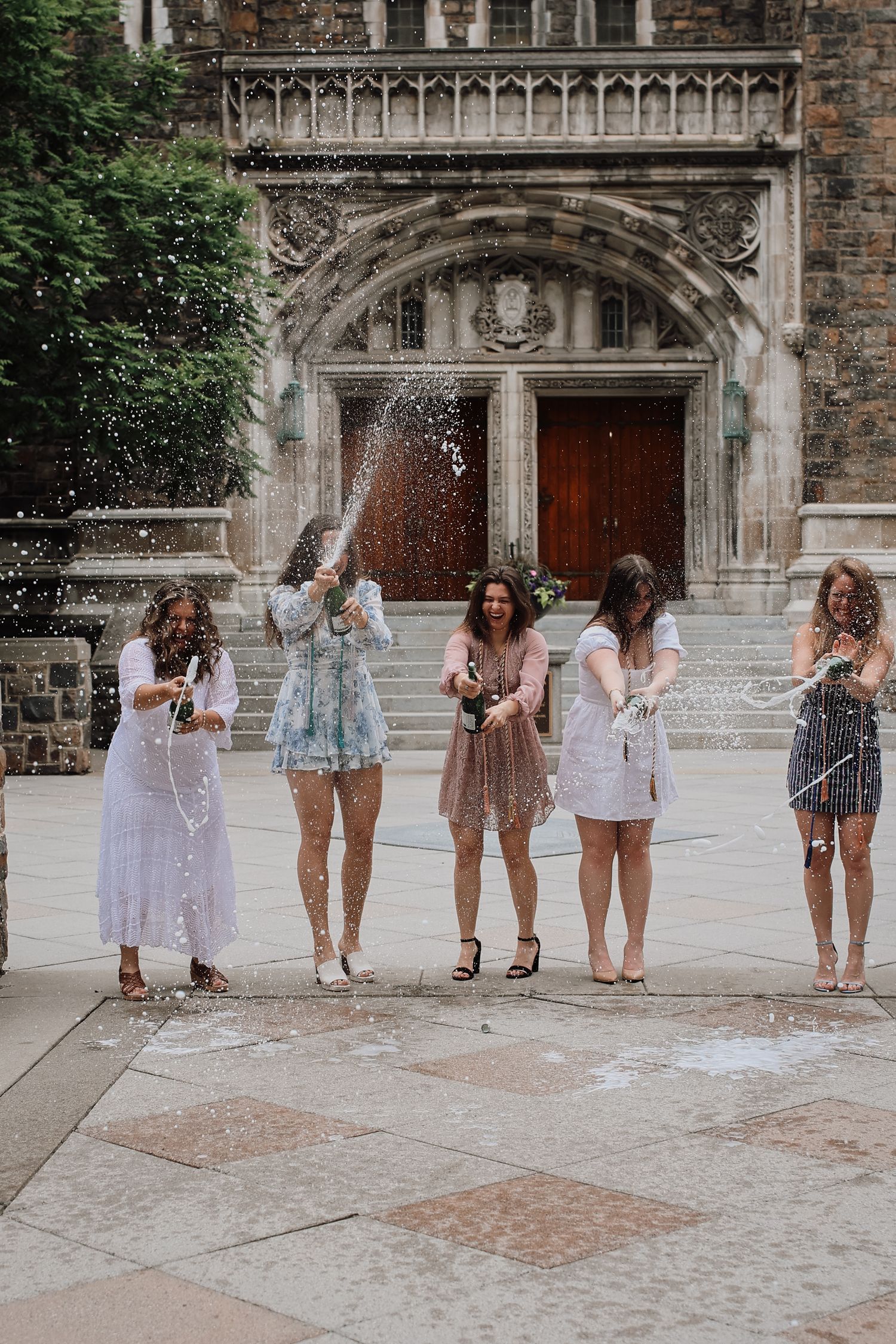 A sequence of photos showing a group of people throwing powder in the air in front of an ornate stone building entrance.