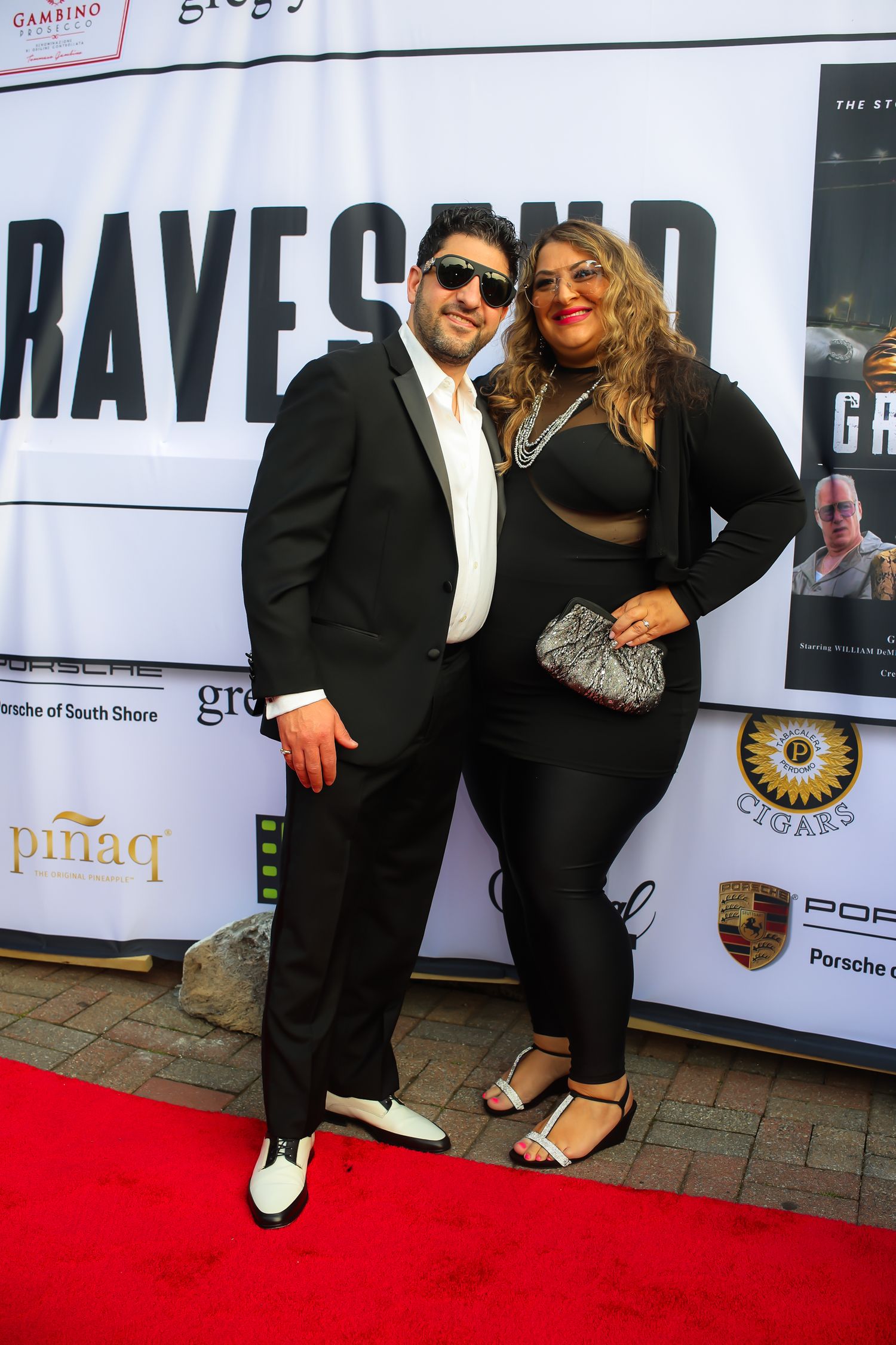 Group of people posing together on red carpet at formal event wearing black and white attire.