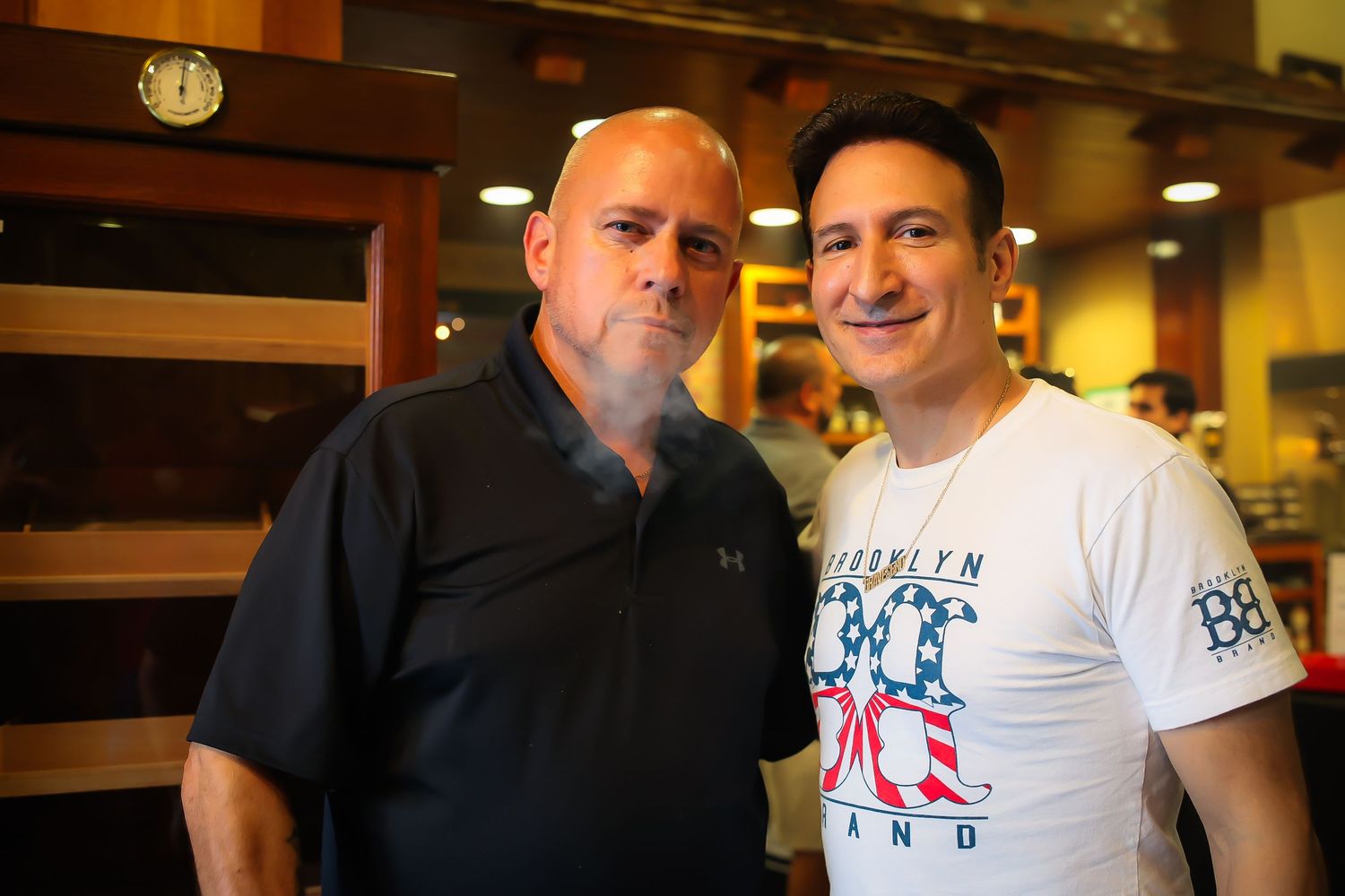 Two people posing together at a restaurant or bar in casual white t-shirts.