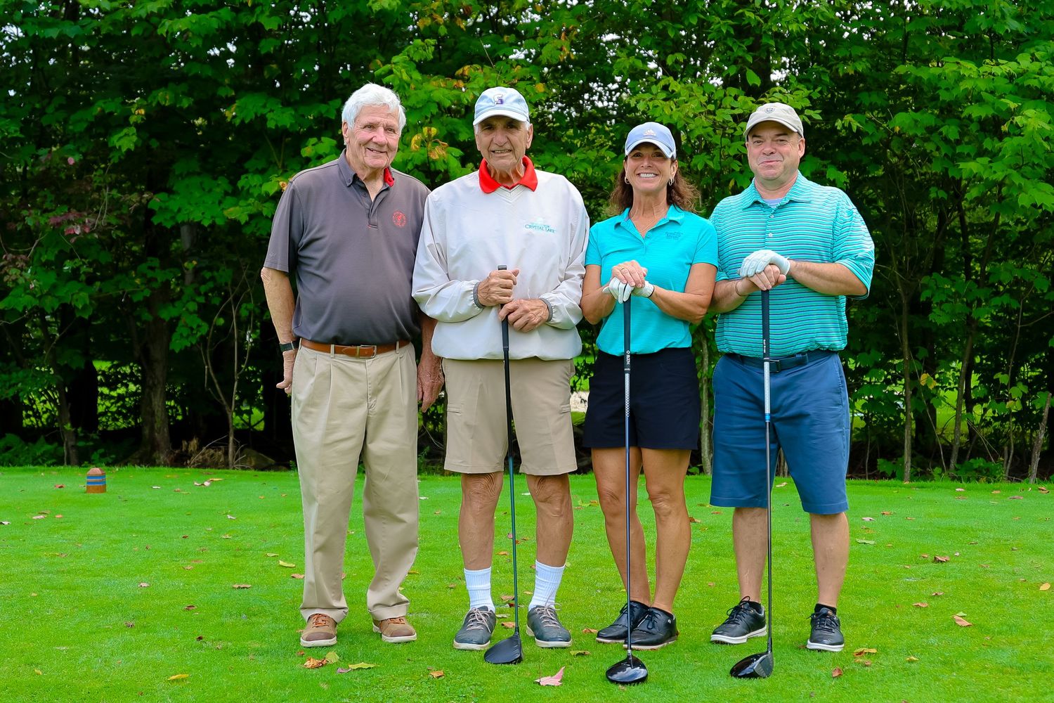 A group of golfers stand together on a lush green course during a sunny summer day.