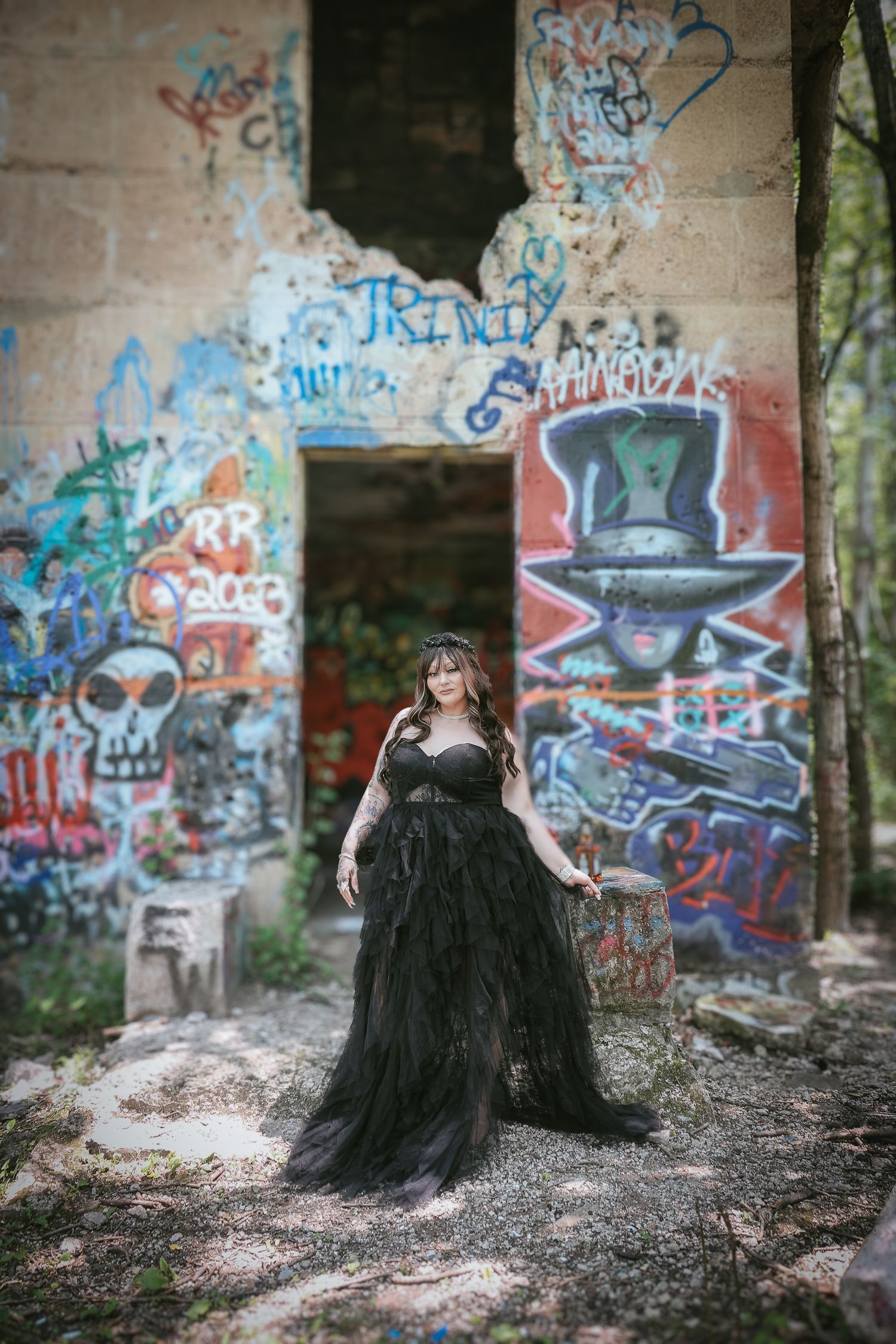 A dark-clad figure poses dramatically against graffiti-covered walls in an abandoned urban setting.