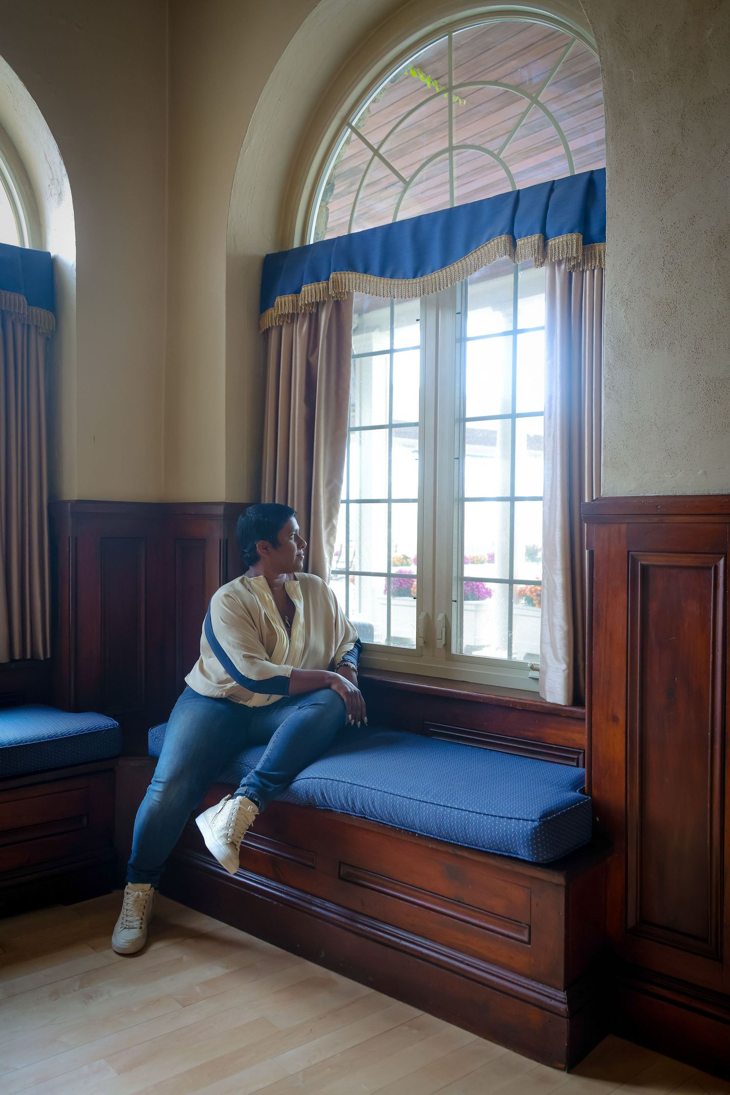 A series of photos showing someone sitting on a built-in window bench with wood paneling and arched windows in a room.