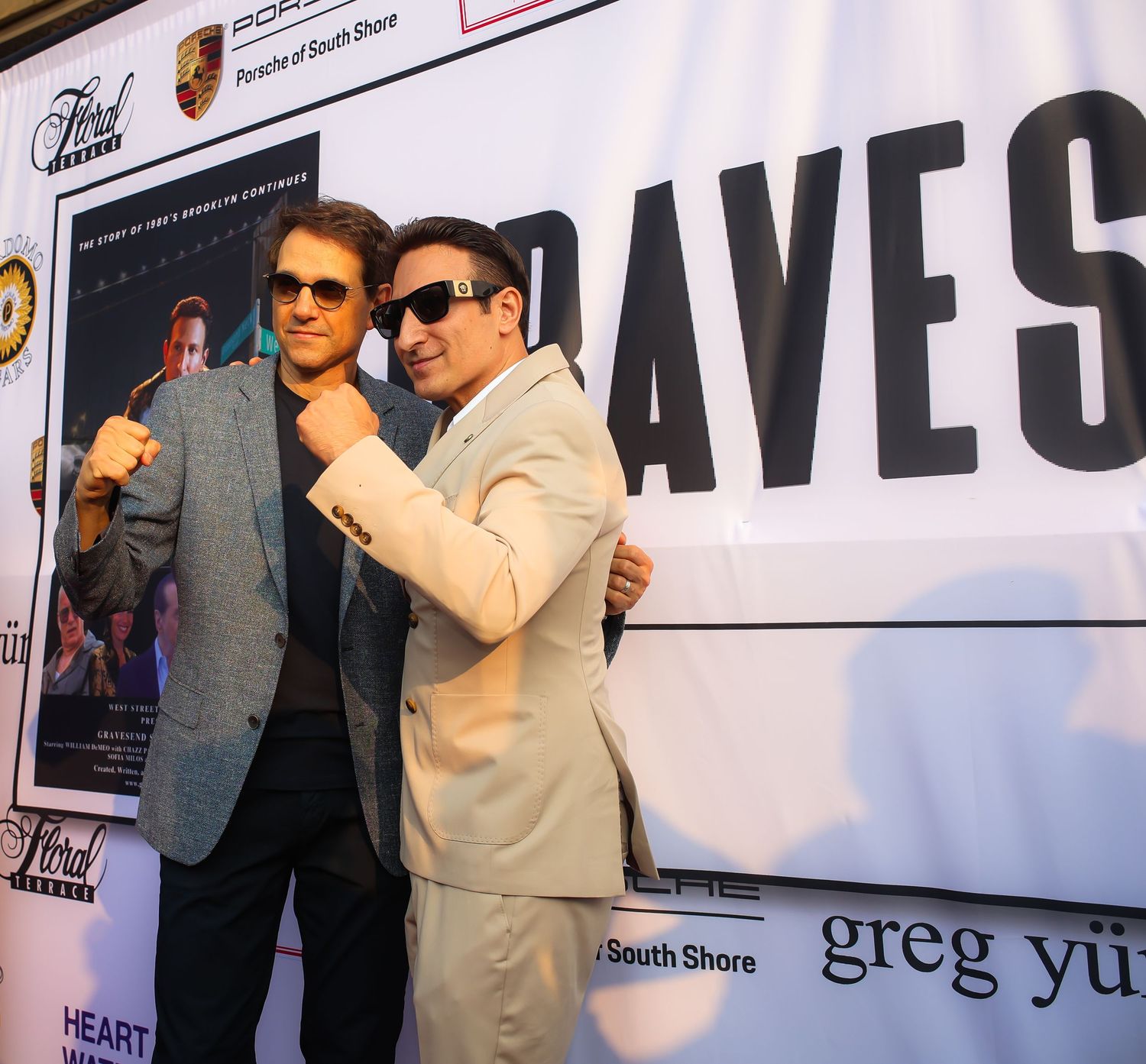A group of people pose together at a promotional event with banners and signage visible in the background.