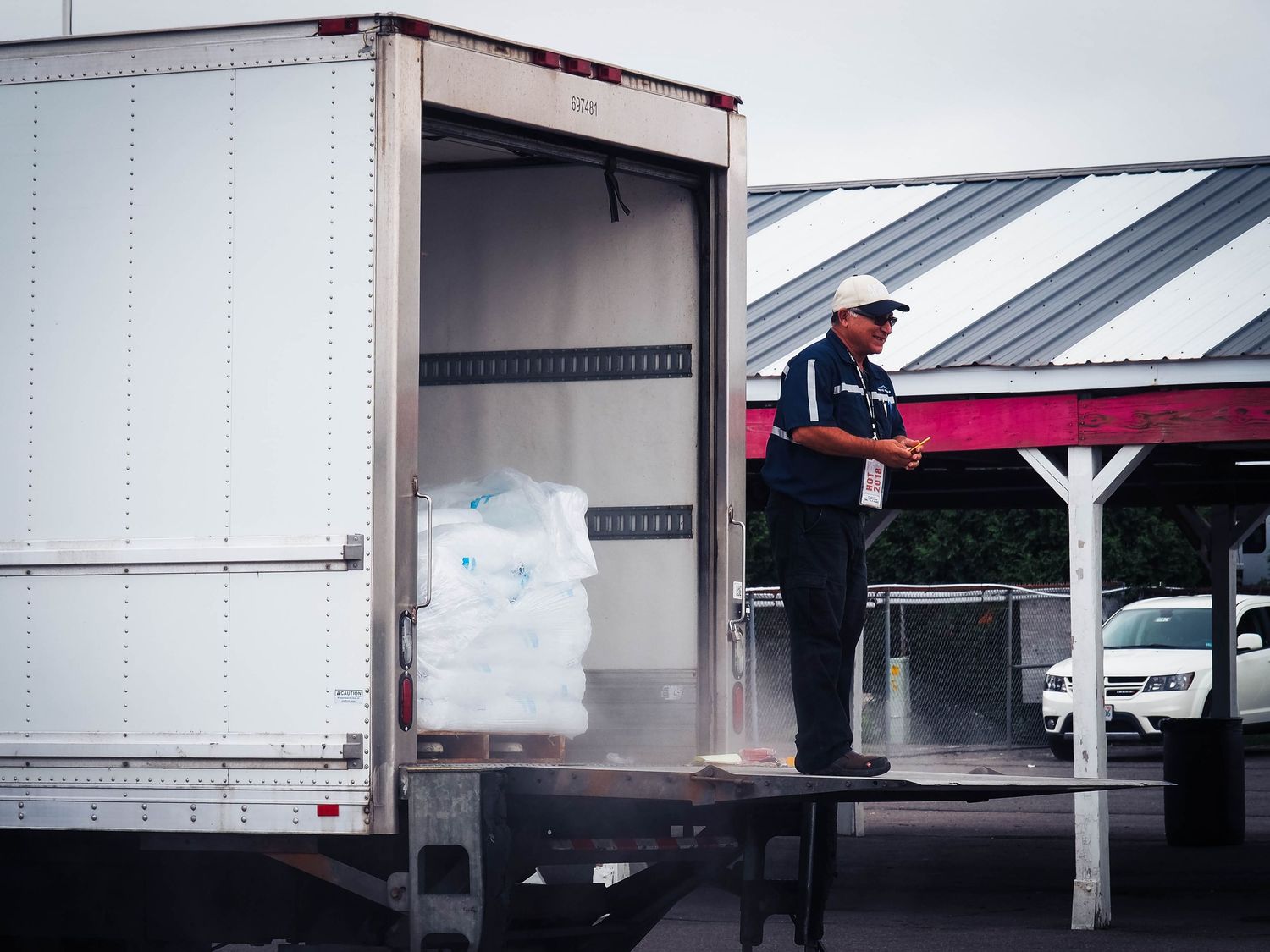 Truck driver adjusts trailer doors and loading dock equipment at a warehouse loading bay area.