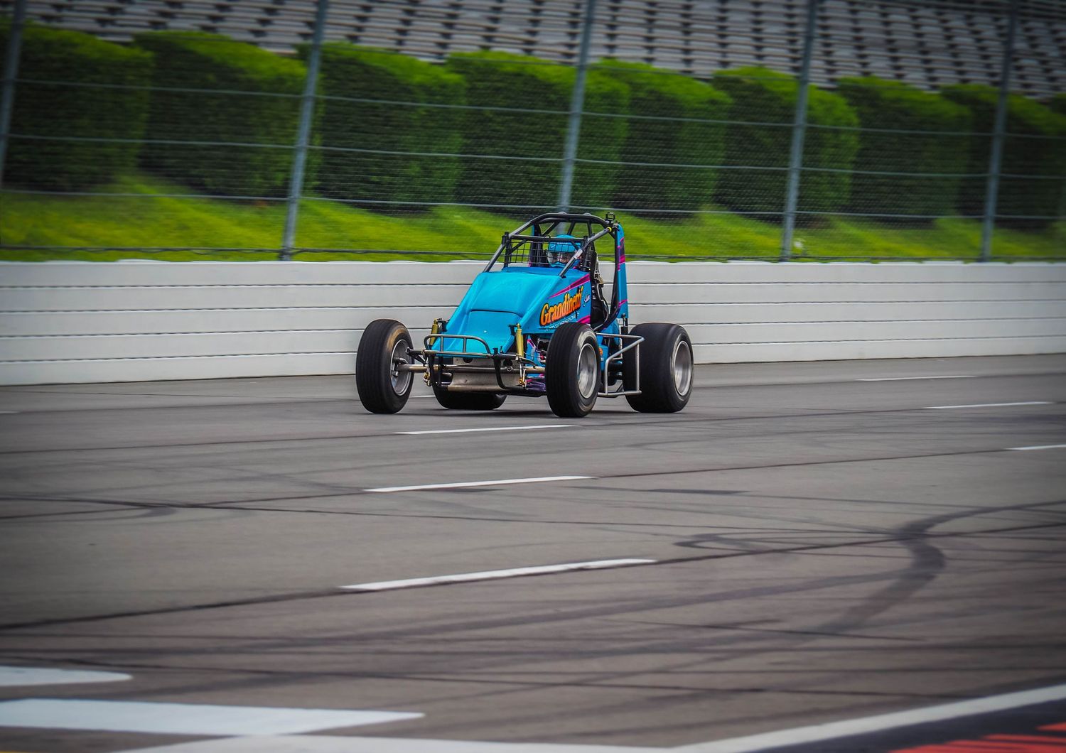 Blue vintage Formula 1 racing car speeds around a racetrack corner during a motorsport competition event.
