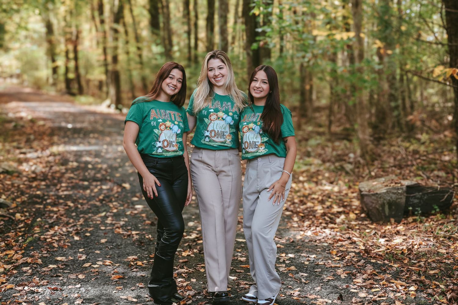 A group wearing matching green and khaki uniforms poses together on a leaf-covered forest path.