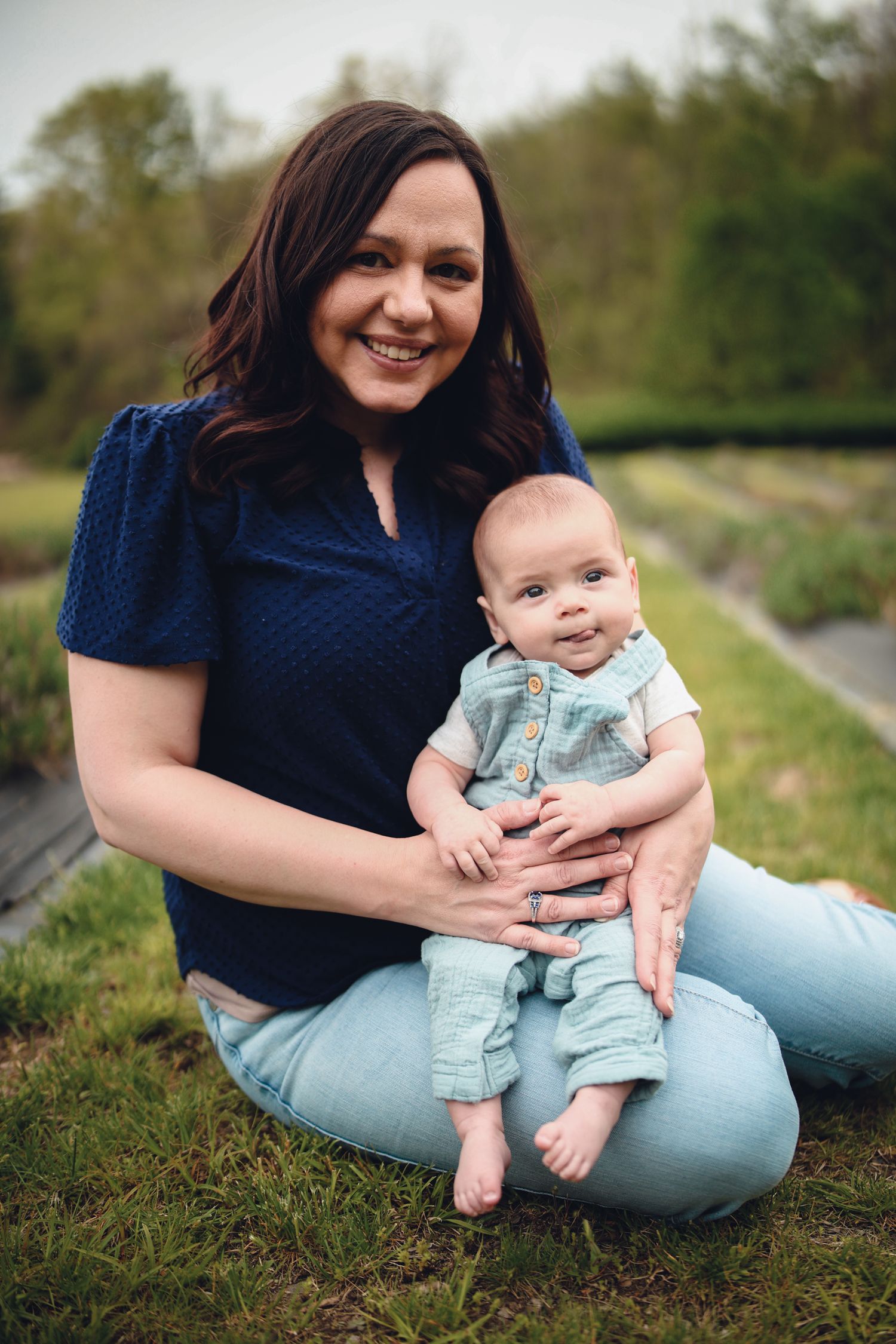 A series of outdoor photos showing a baby in light blue overalls being held while sitting on grass.