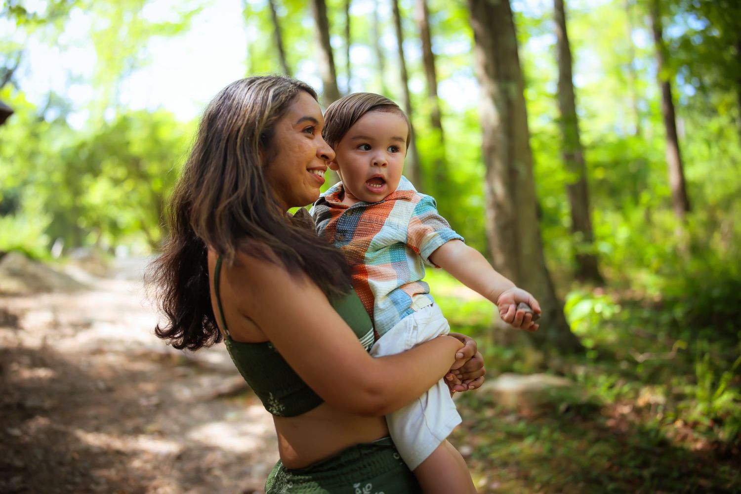 Mother and baby share tender moments while exploring a sunlit forest path together.