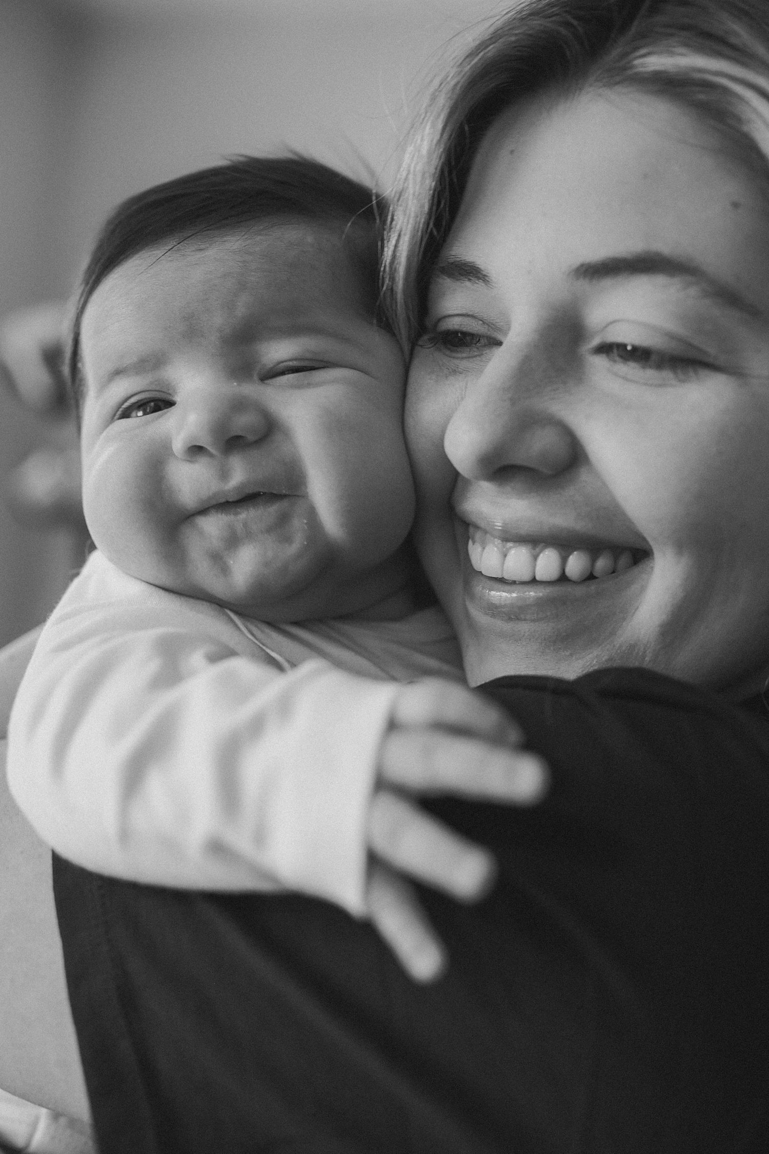 A black and white photo series showing tender moments of affection and smiles between a parent and baby.