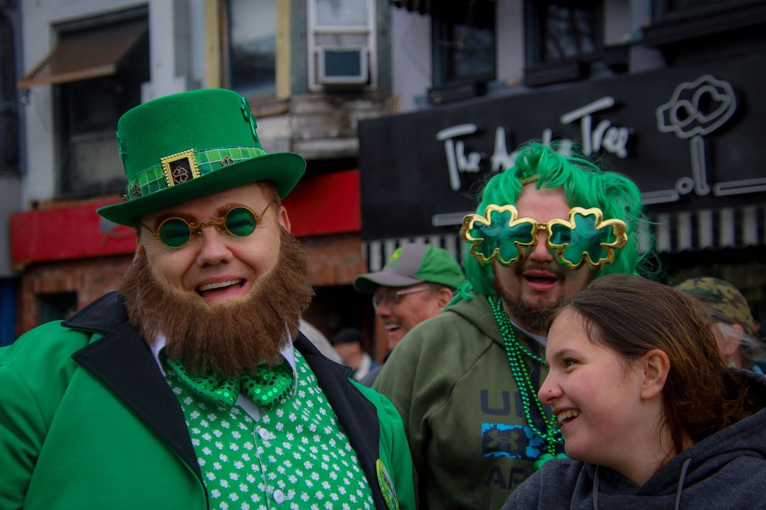 People dressed in festive green clothing and hats celebrate St. Patrick's Day with smiles and Irish spirit.