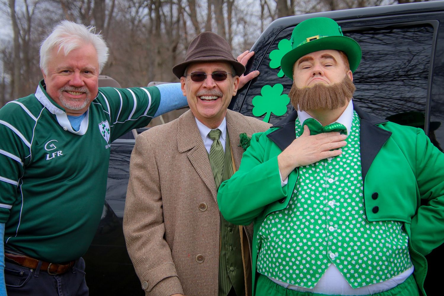 People wearing festive green clothing and shamrock accessories celebrate at a St. Patrick's Day parade event.