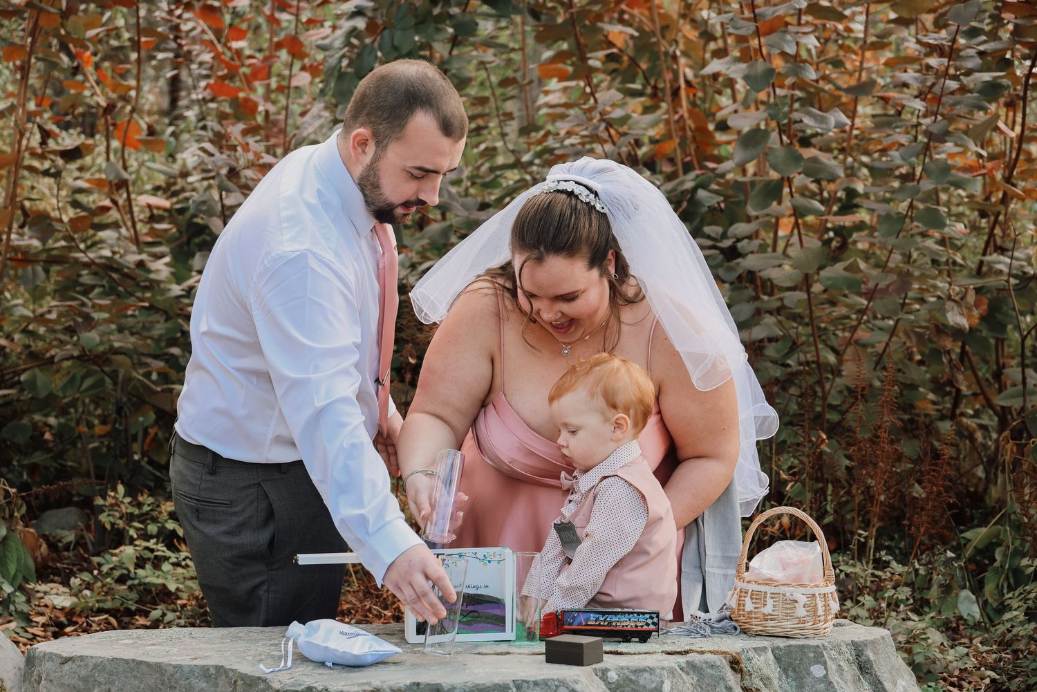 Wedding party plays a board game during outdoor reception with autumn foliage in background.