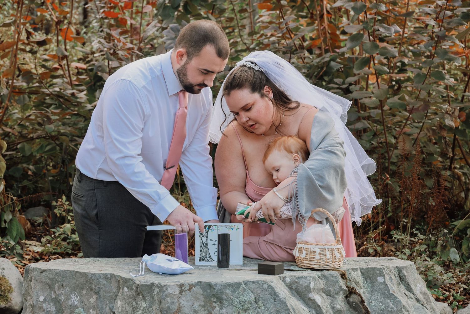 A couple shares romantic moments in a garden setting with autumn foliage in the background.