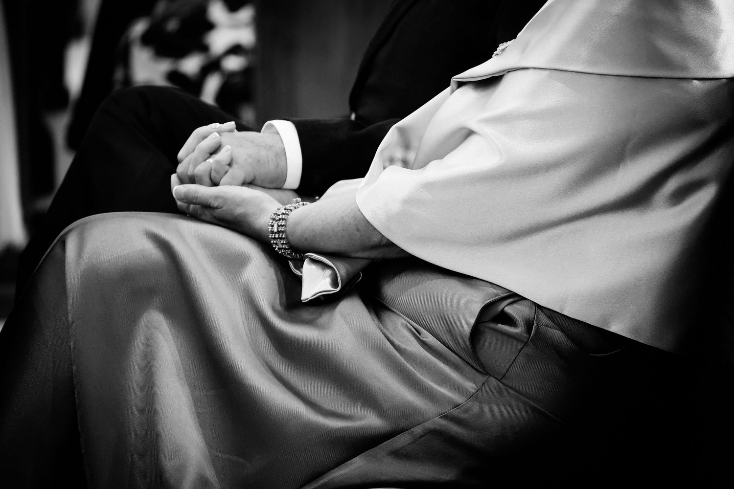 Black and white photo of hands exchanging wedding rings during an intimate marriage ceremony.