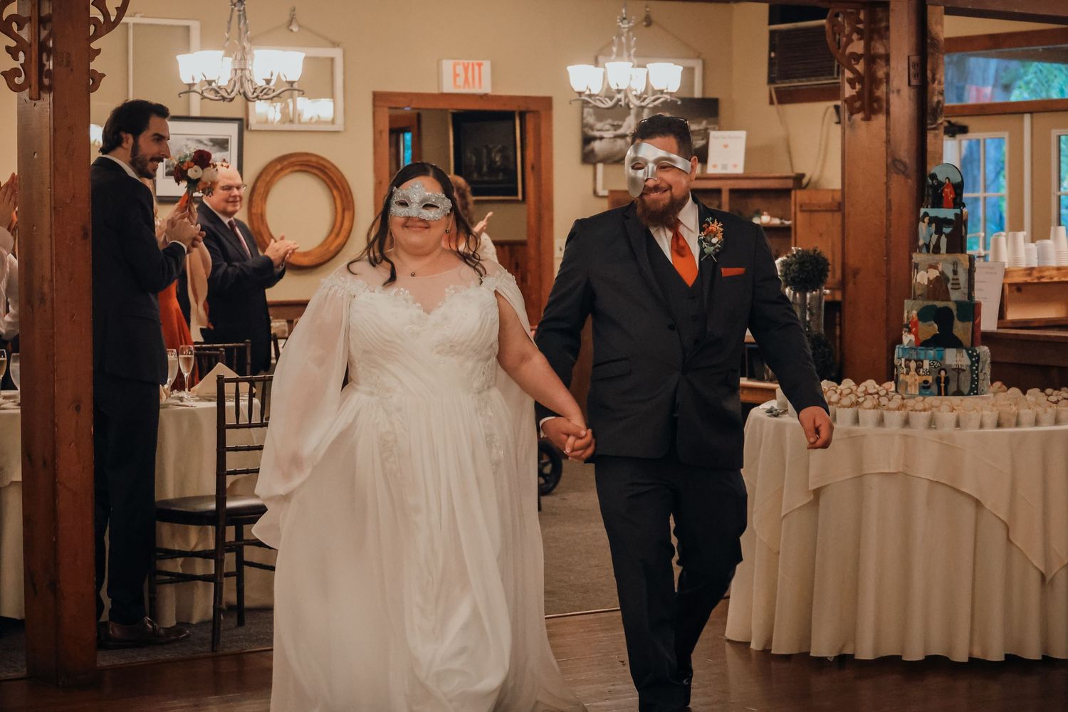Wedding guests dancing and celebrating together at an elegant reception venue with chandeliers and warm lighting.