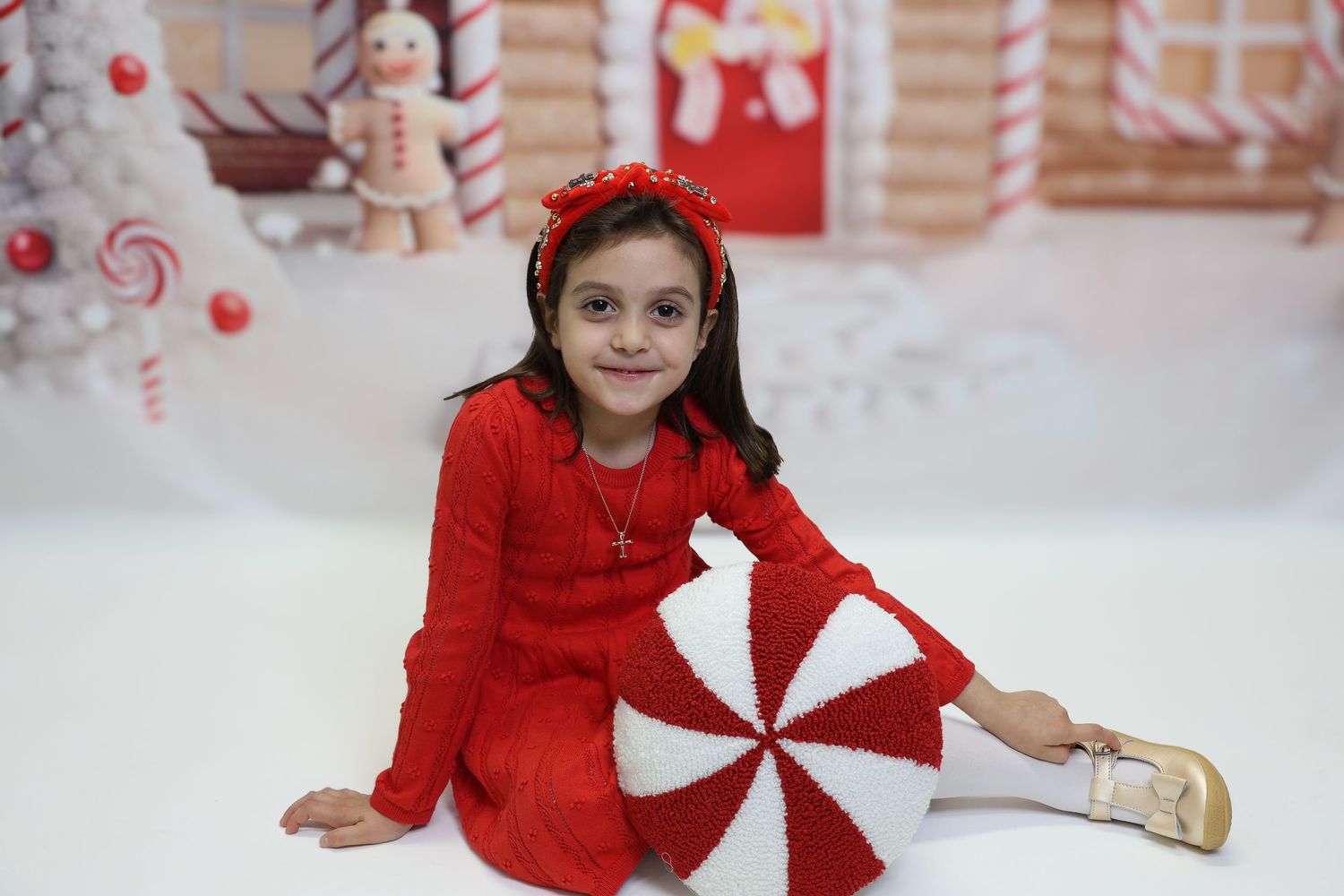 A collage of photos showing someone in a red dress posing against a festive peppermint and candy cane themed backdrop.
