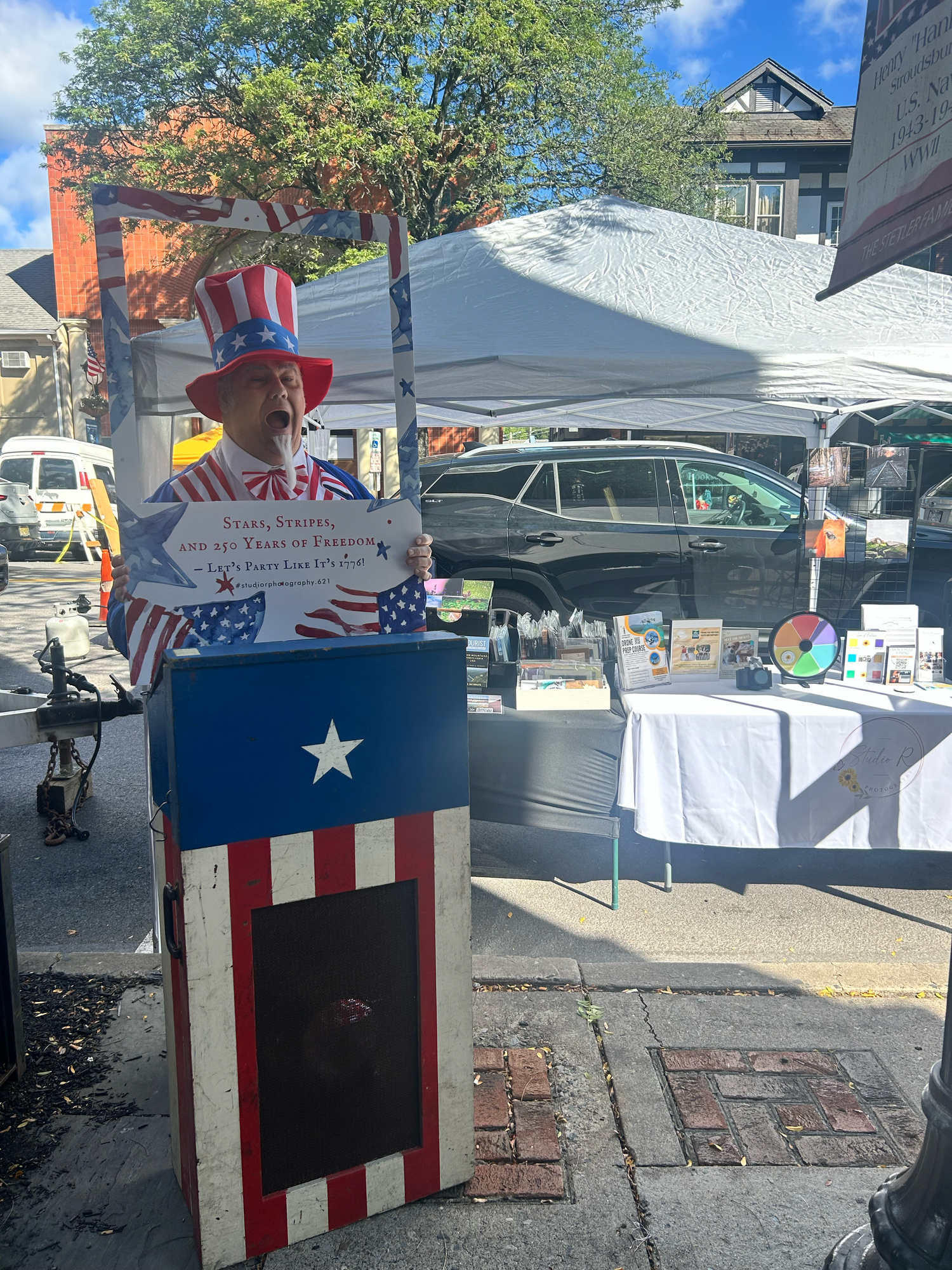 Patriotic red white and blue carnival booth with American flag design standing outdoors at a local fair or festival.