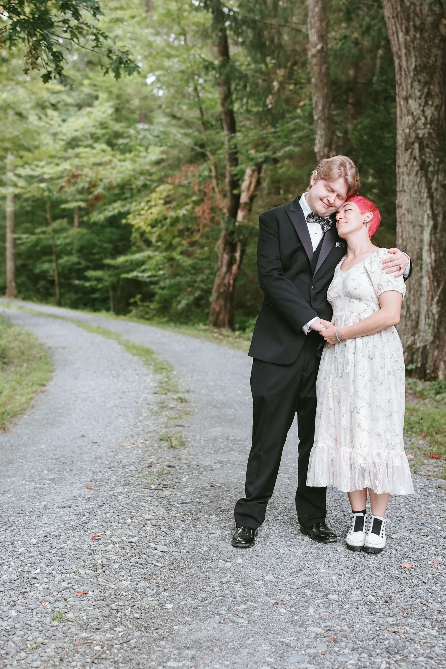 A couple in formal attire shares intimate moments along a scenic forest path in a series of romantic photographs.