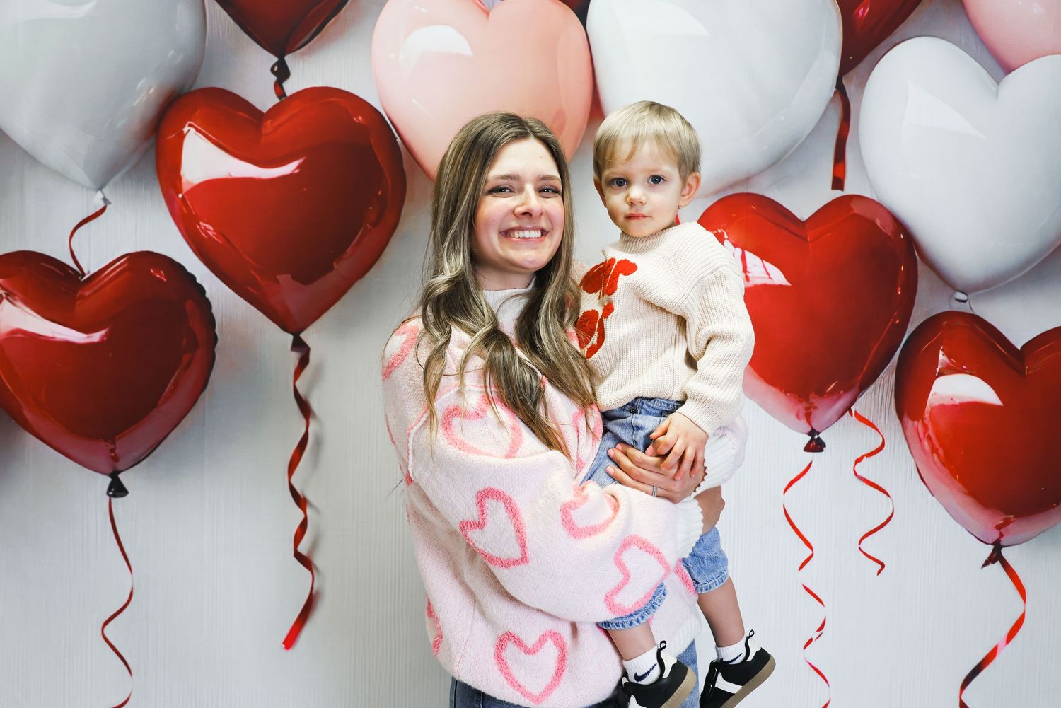 A festive Valentine's Day scene with heart-shaped balloons in red and white creating a romantic backdrop.