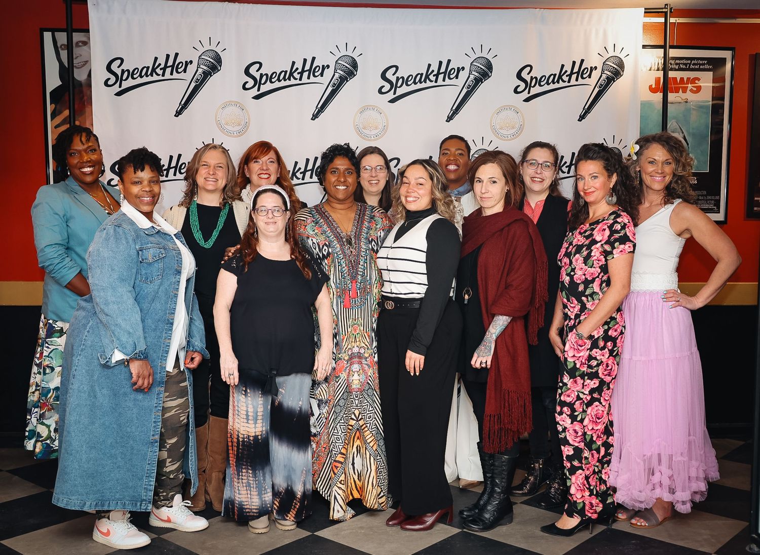 Group of women posing together at a SpeakHer event in front of branded backdrop.