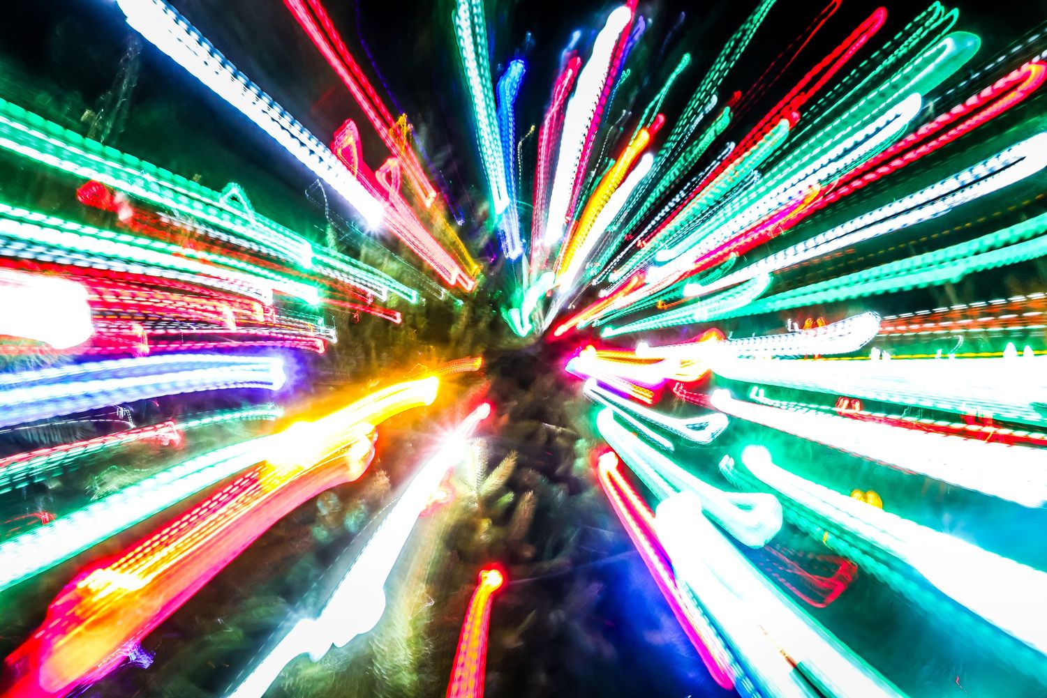 Abstract light trails create a colorful burst pattern with red, green and blue streaks zooming toward the center.