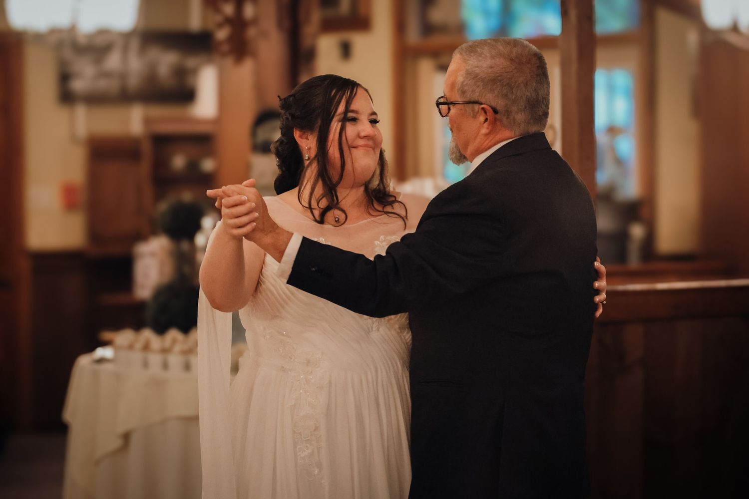A couple shares a romantic dance together during a wedding reception in a warmly lit venue.