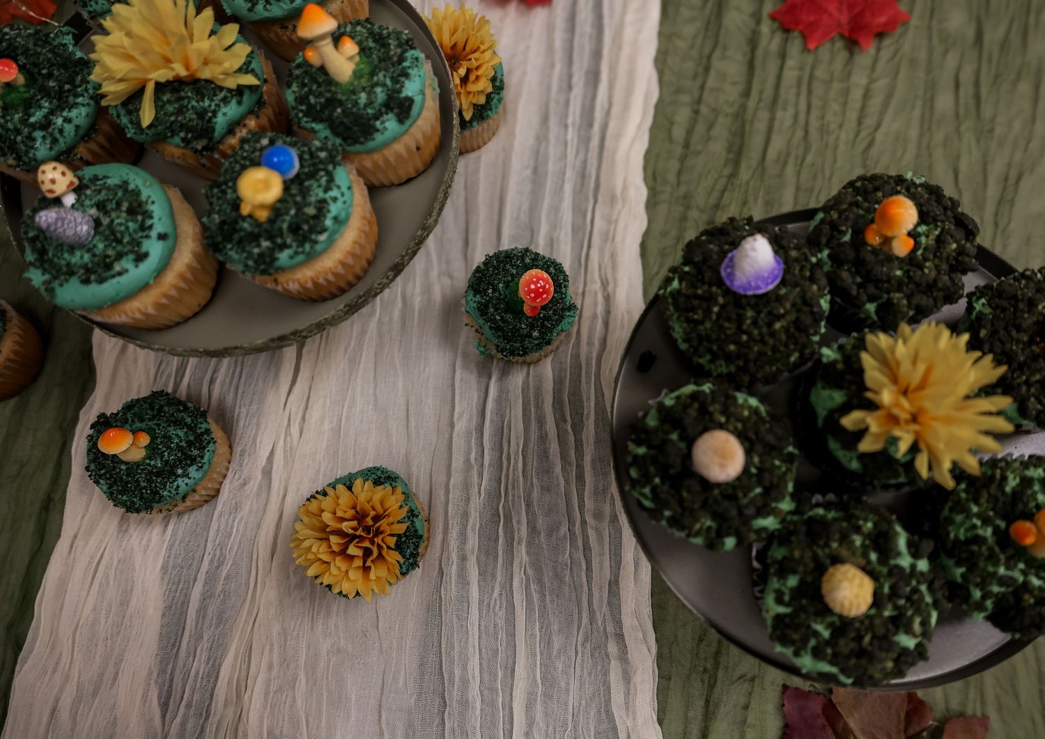 Overhead view of chocolate cupcakes decorated with orange and yellow flowers on a rustic wooden surface.