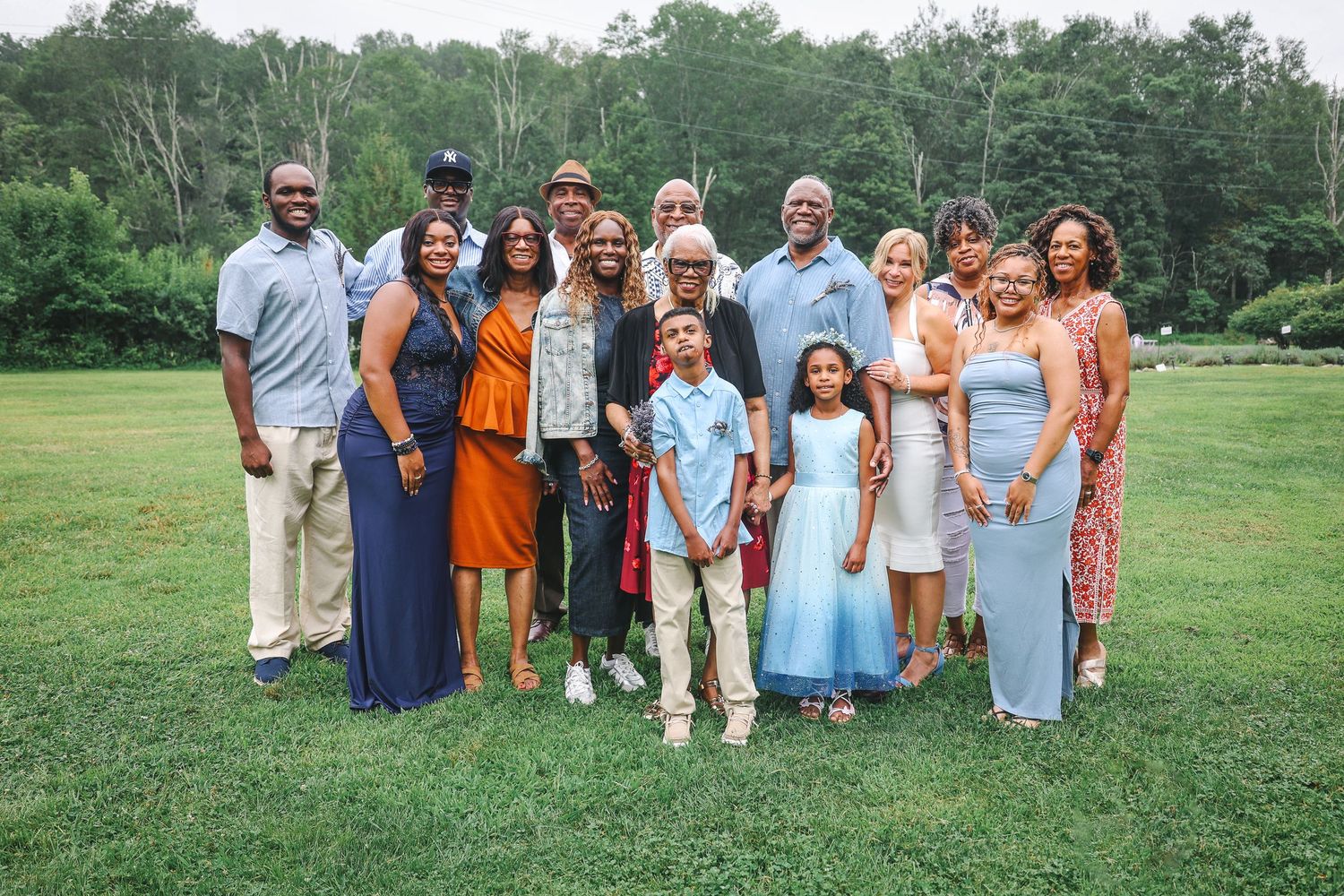 A group of people wearing coordinated orange, blue and white outfits pose together on a grassy field.