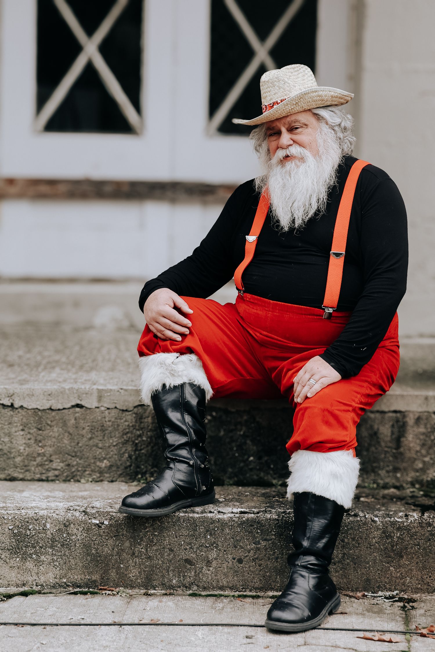 Person wearing black boots, red pants with orange suspenders sits on concrete steps in artistic composition.