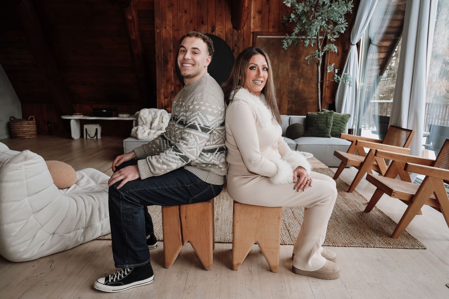 Couple in wedding attire sitting in wooden chairs share intimate moments in rustic indoor setting.