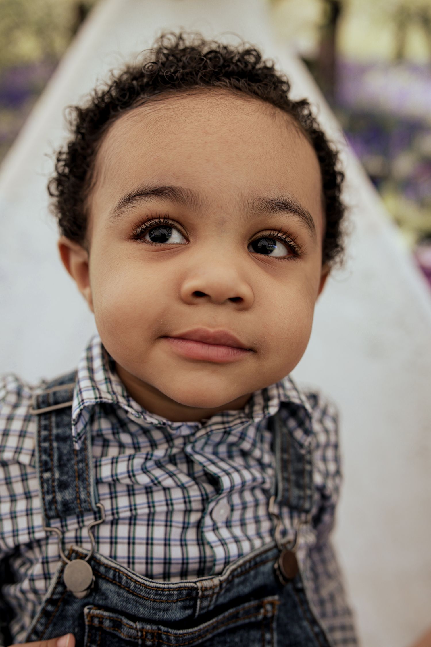 A young child in a checkered shirt looks upward with a gentle expression in a series of close-up portrait shots.