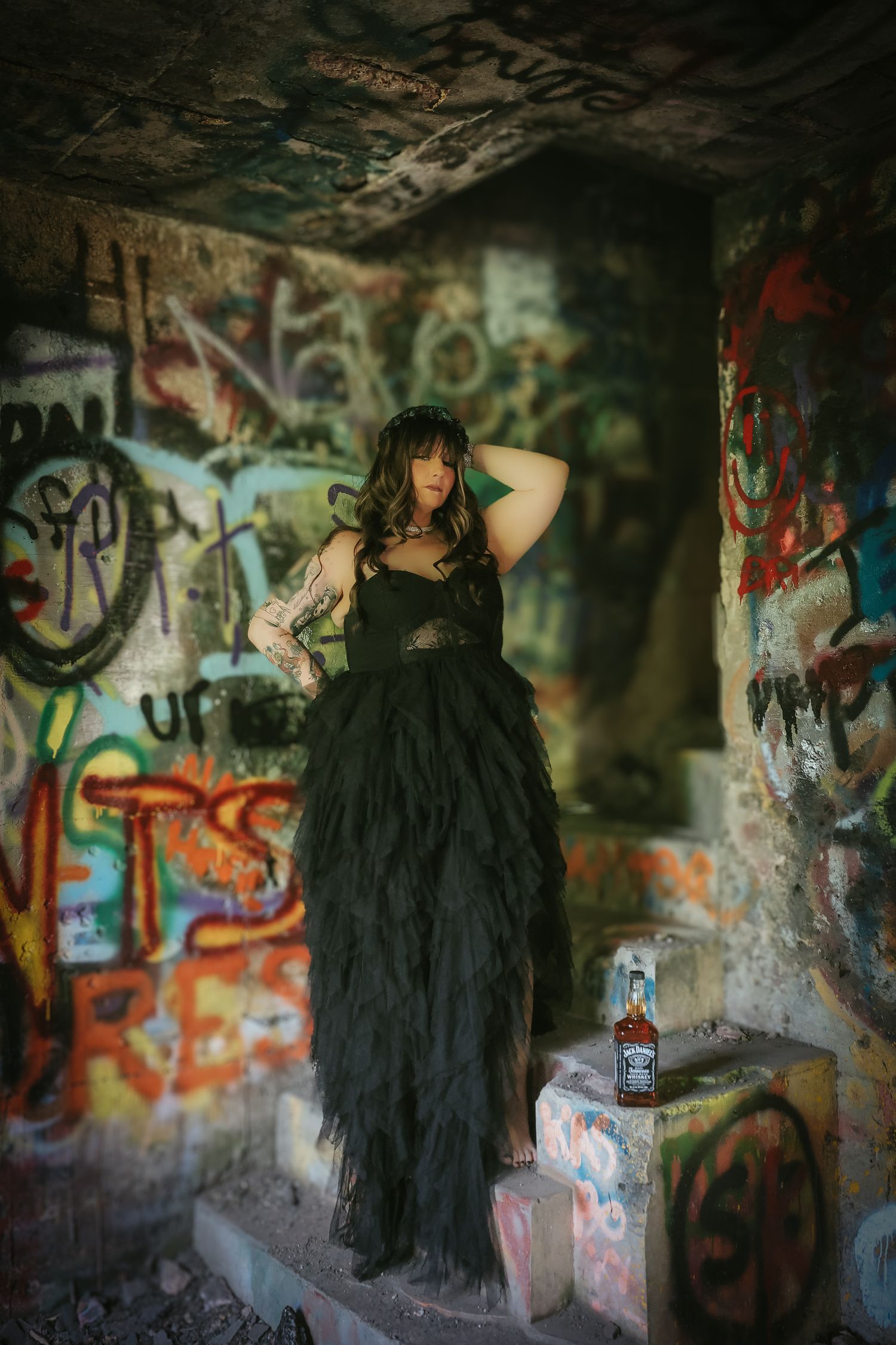 Dark figure in black clothing poses against graffiti-covered tunnel walls in moody atmospheric photo series.