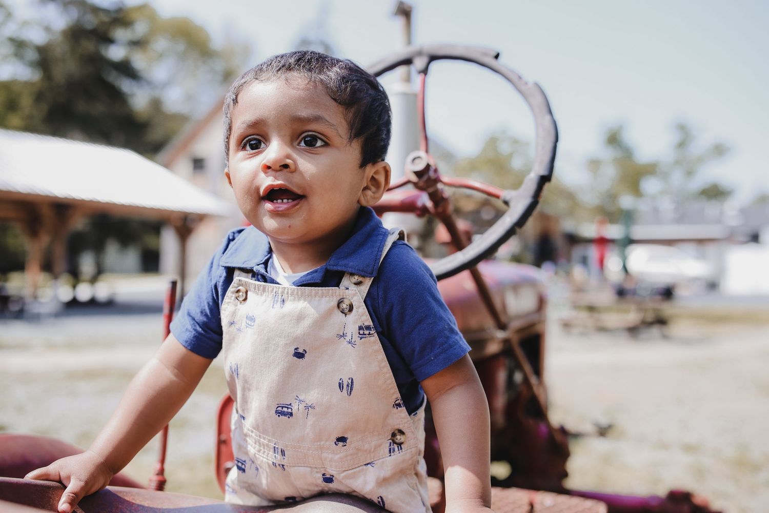 A young child plays with a large hoop toy outdoors on a sunny day.