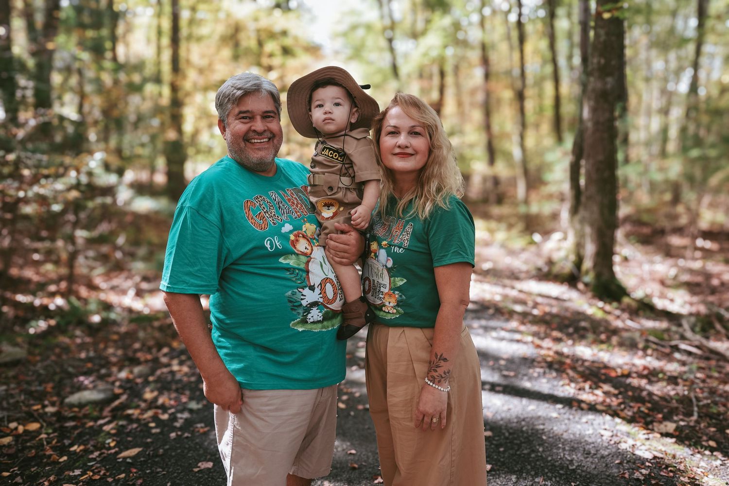 People in coordinated teal outfits share joyful moments together during an outdoor forest photoshoot.