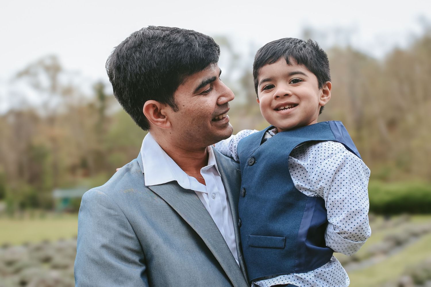 A loving moment between parent and child sharing playful interactions outdoors in a park setting.