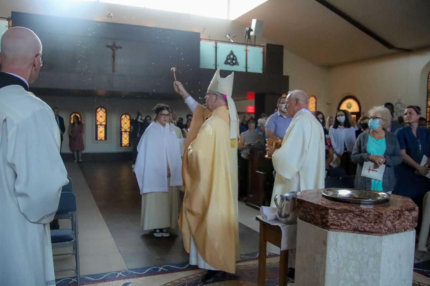 Religious figures in white and gold vestments perform a ceremony at a church altar.