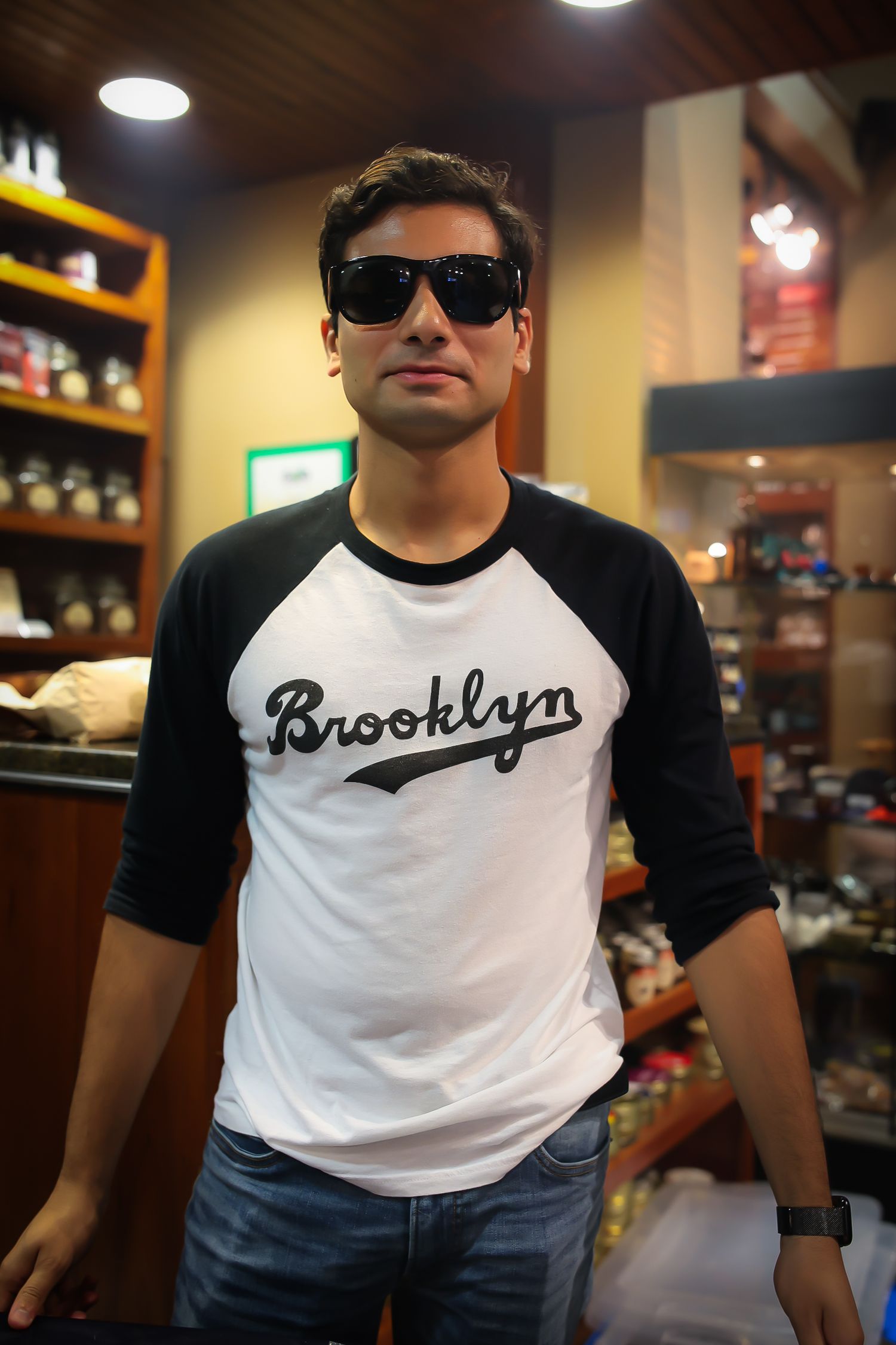 A person wearing a Brooklyn t-shirt and sunglasses stands in what appears to be a retail store interior.