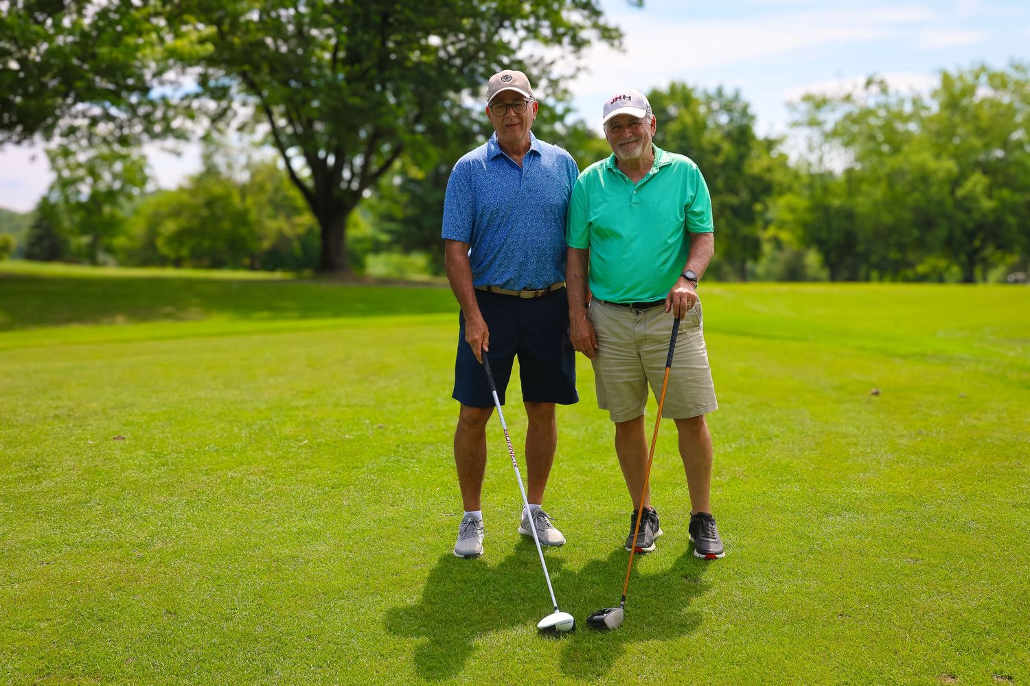 Group of golfers standing together on a lush green golf course on a sunny summer day.