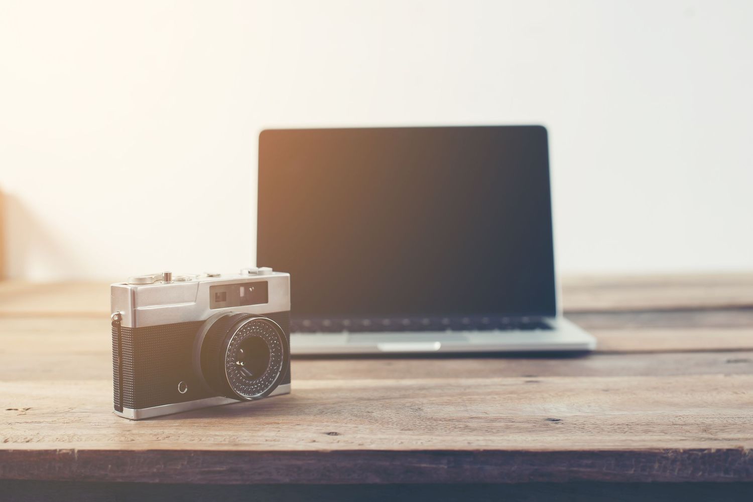 A vintage film camera sits on a wooden surface with dramatic lighting and shallow depth of field.