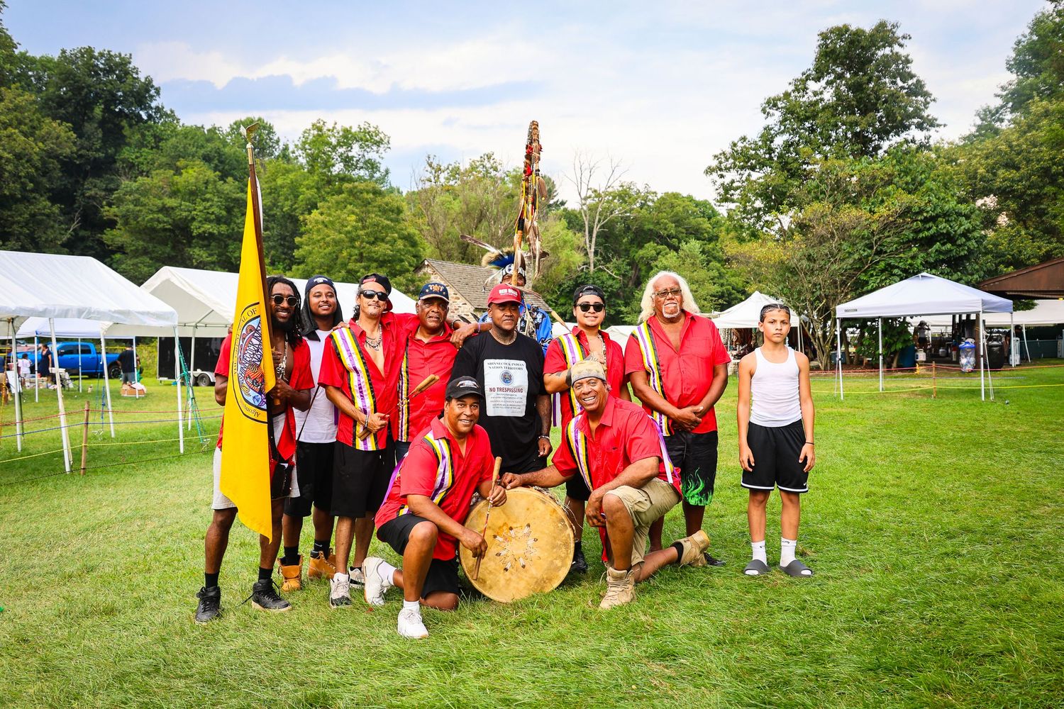 Team members participate in outdoor field day activities wearing red and white uniforms on a sunny grassy field.