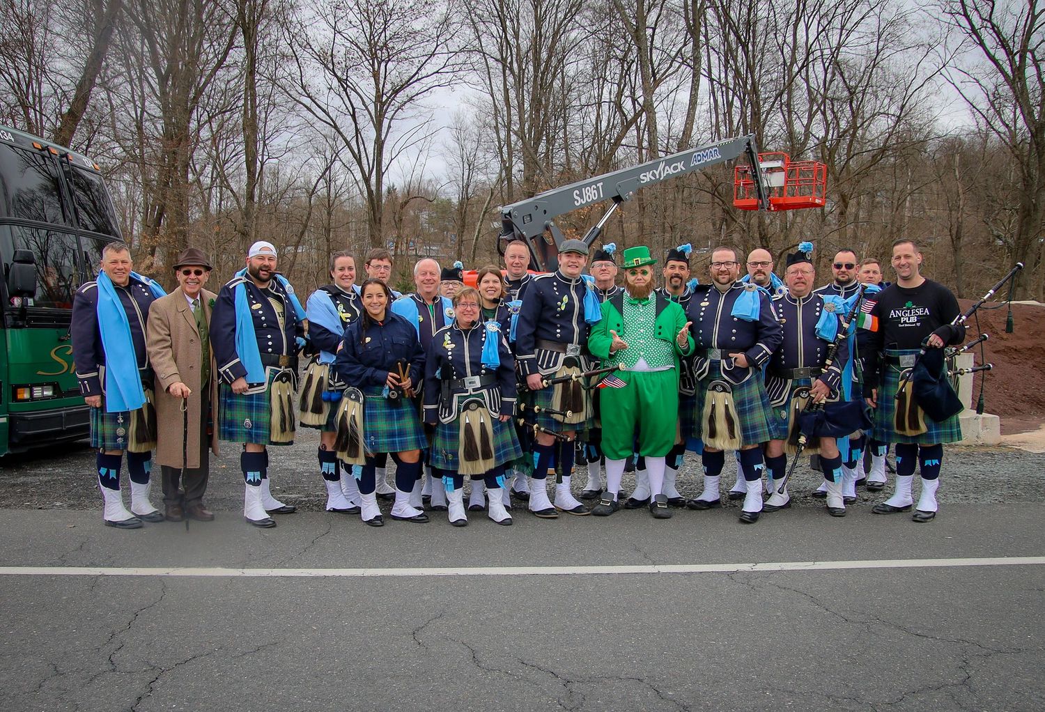 A line of students in blue and green uniforms stand together outdoors during a school gathering.