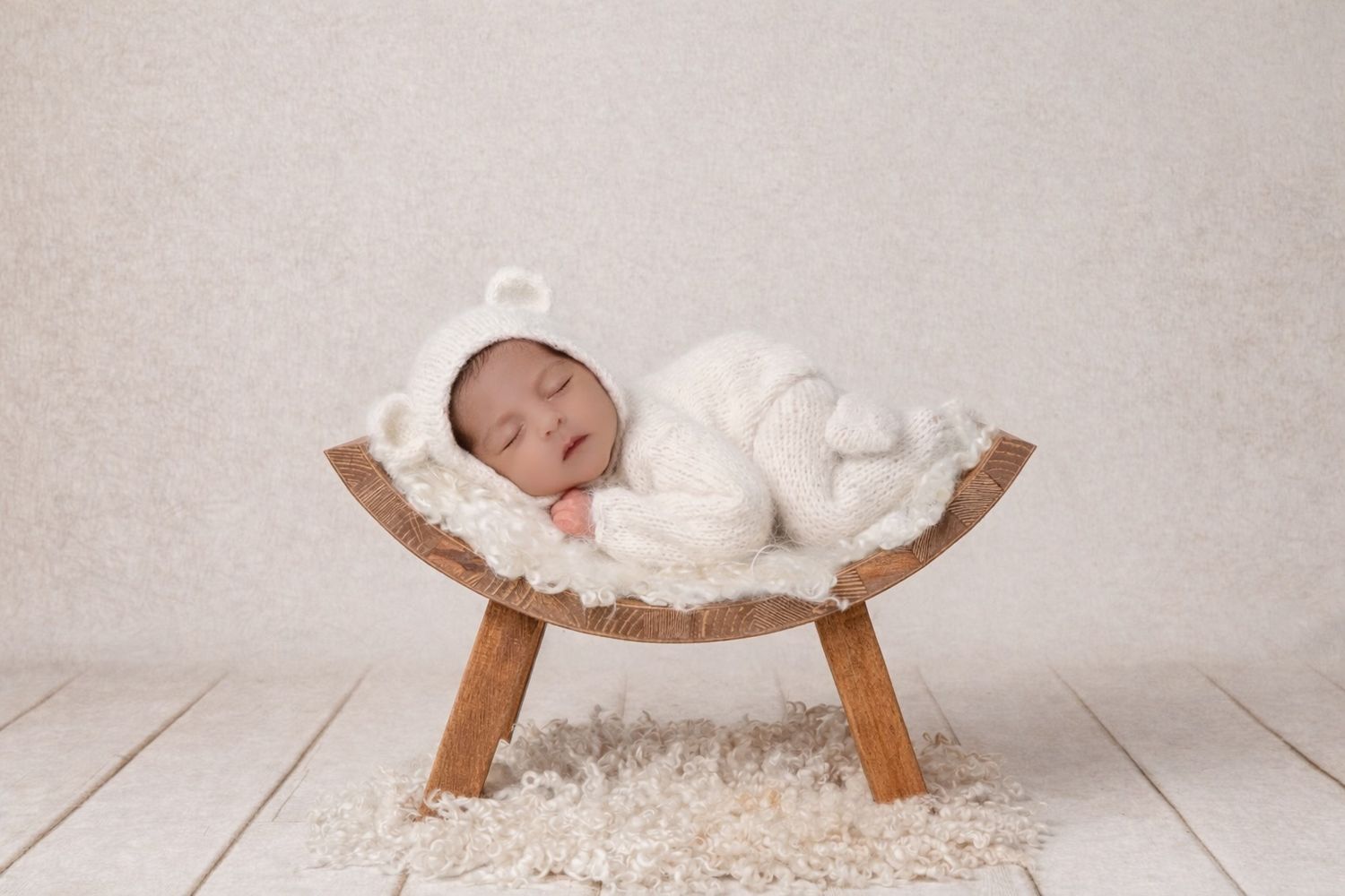 Rustic wooden photography props with white textiles arranged for newborn photos.