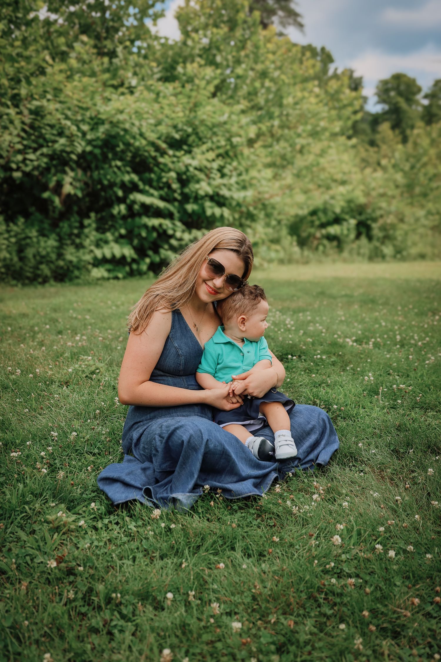 A tender moment shared between two people sitting together on green grass in a park setting.