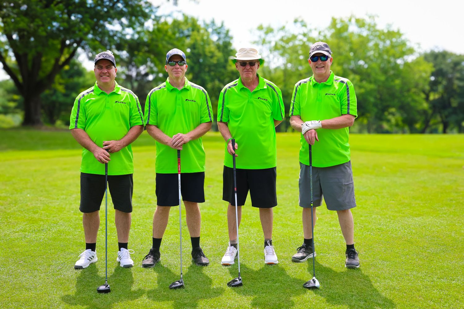 Group of golfers wearing bright neon green shirts standing together on a lush golf course fairway.