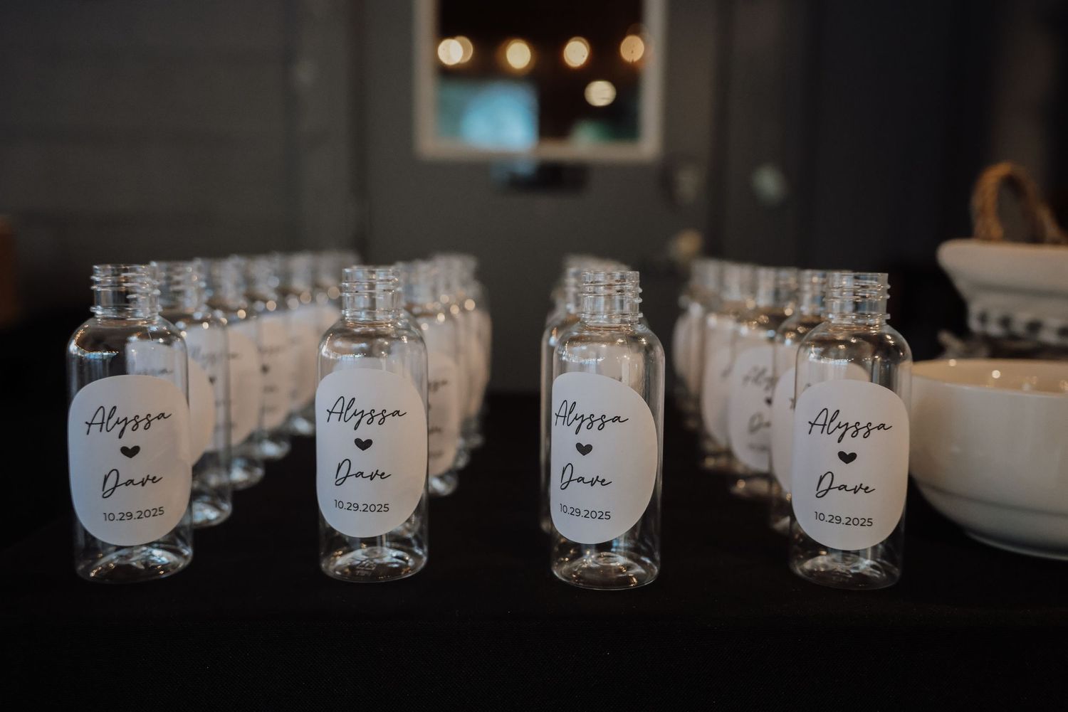 A row of handwritten name cards with elegant calligraphy displayed on a dark surface with bokeh lights in background.