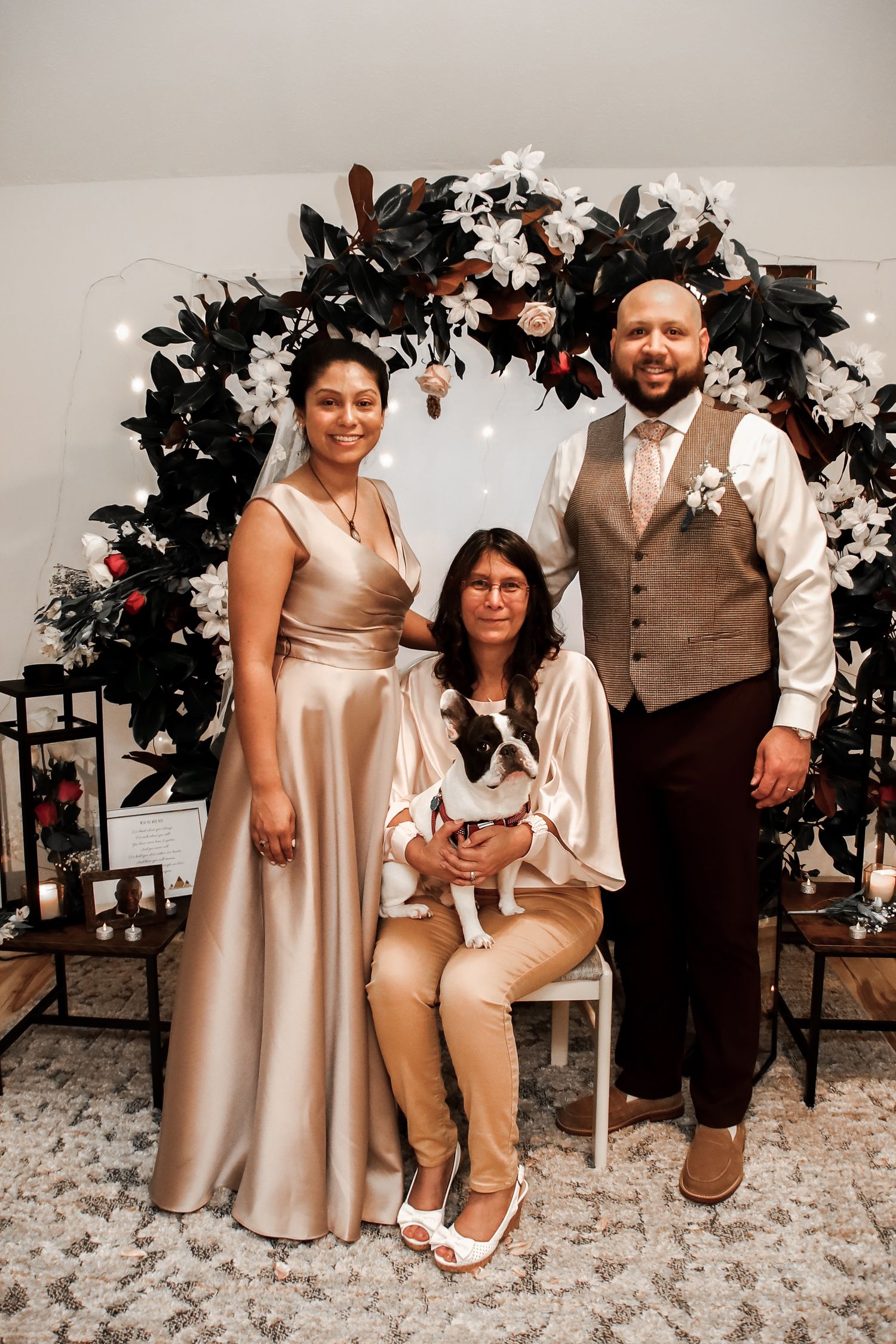 Four candid family portraits in front of a floral backdrop showing coordinated beige and brown outfits at a special occasion.