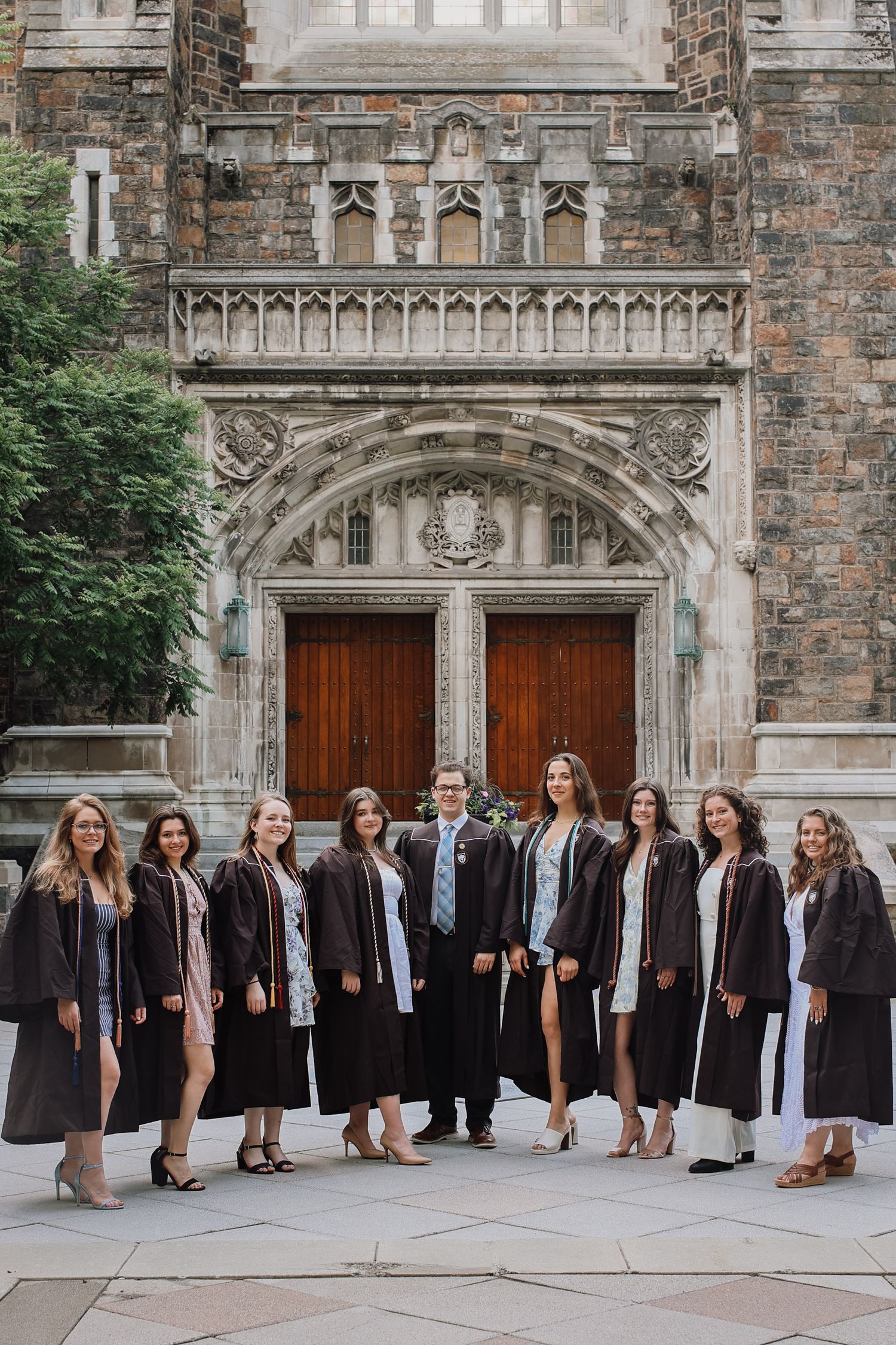 A large group poses in formal attire in front of a gothic stone church building with ornate architecture.