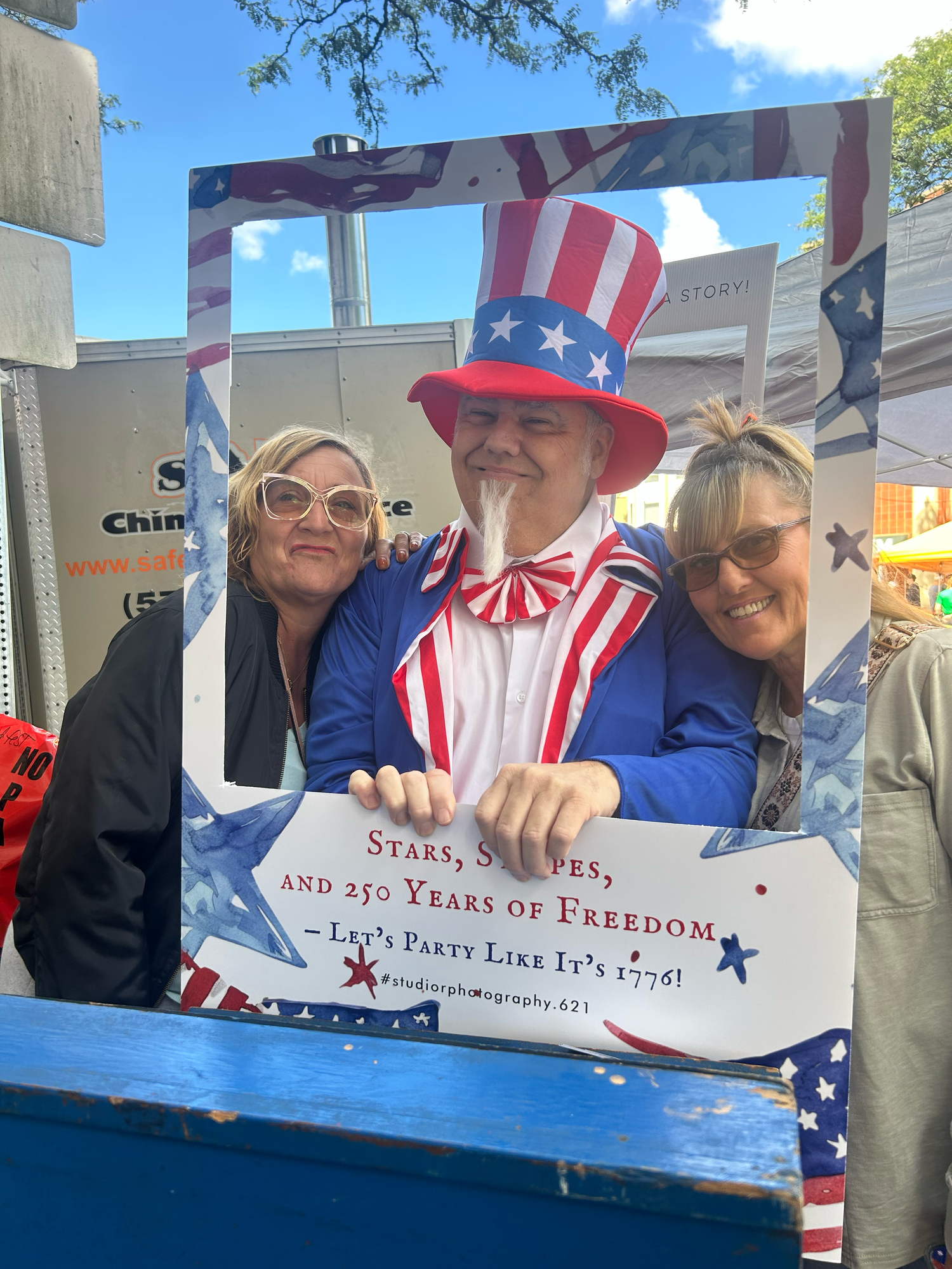 A patriotic group poses with American flag themed decorations and costumes at an outdoor event.