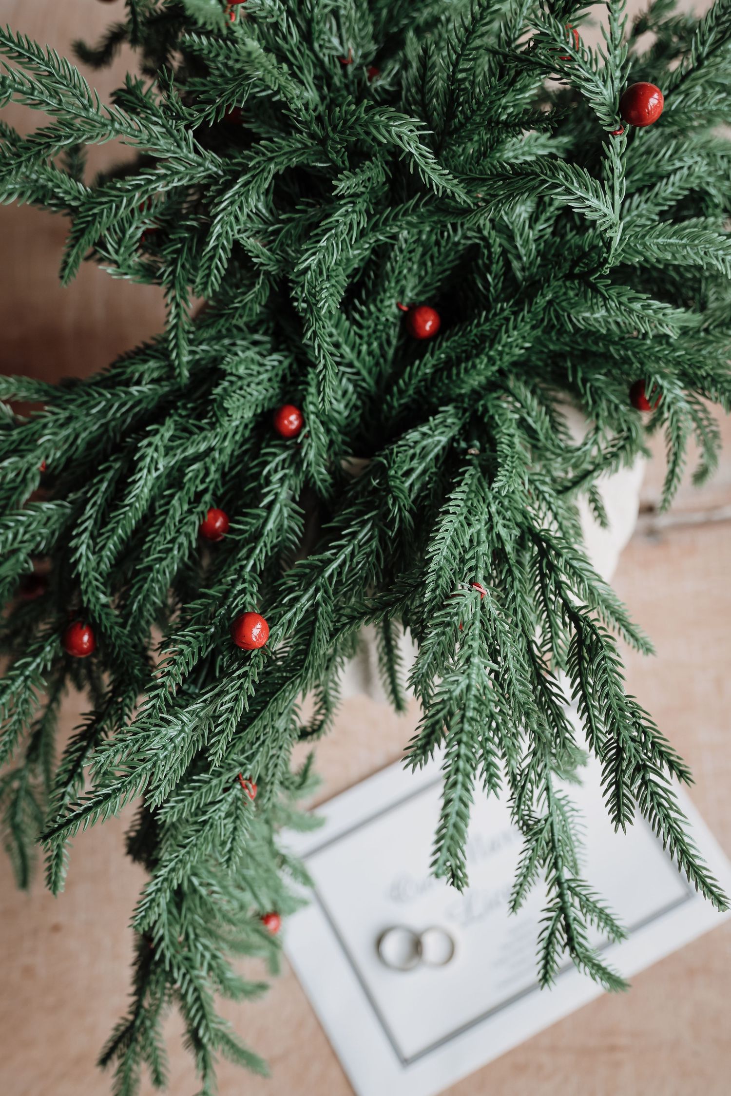 Fresh evergreen branches with red Christmas ornaments arranged in a white decorative planter for holiday decor.