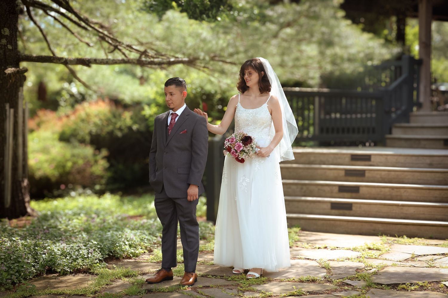 A bride and groom share a romantic moment in a lush garden setting during their outdoor wedding ceremony.